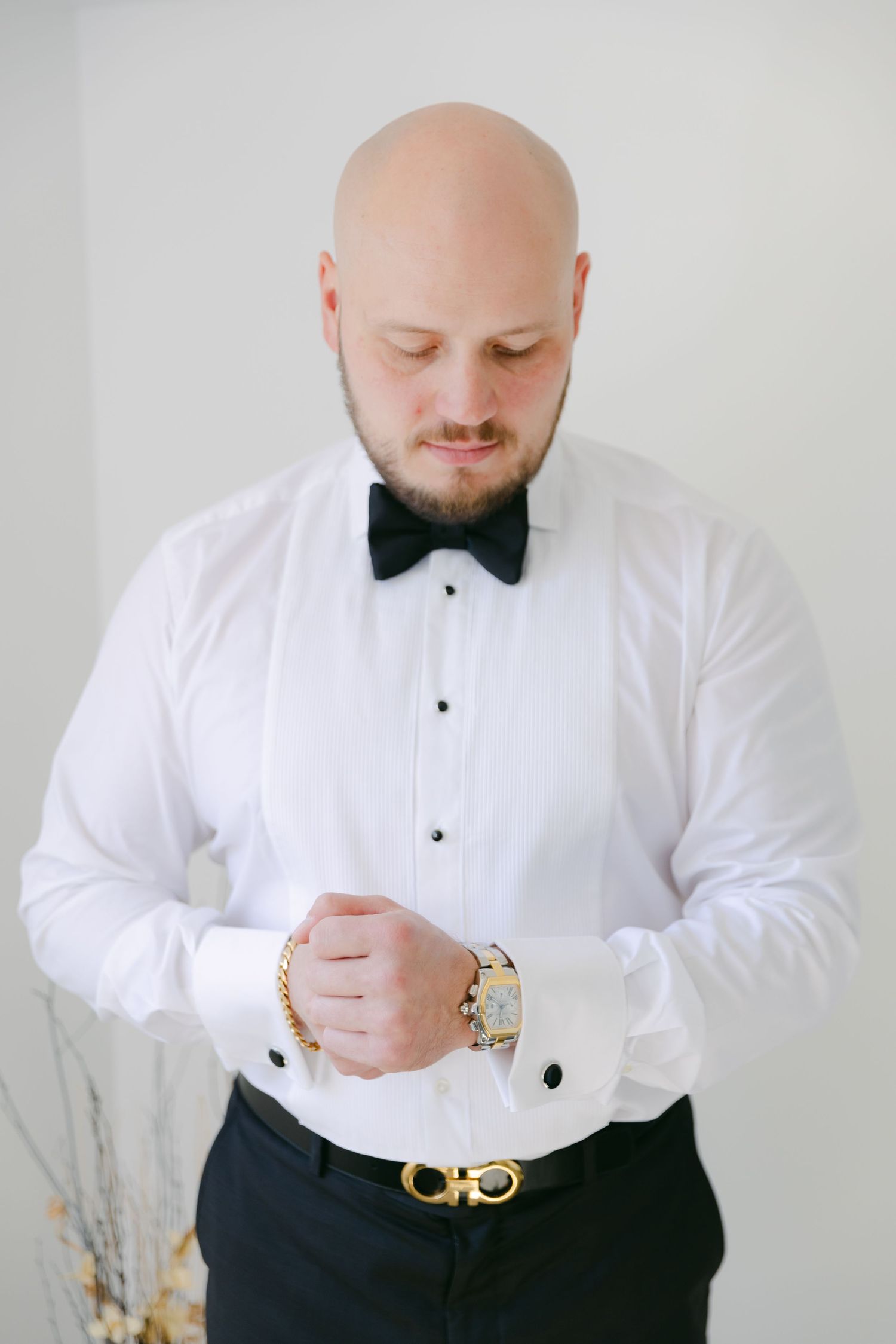 Person in formal white shirt and bow tie looking down at their watch.