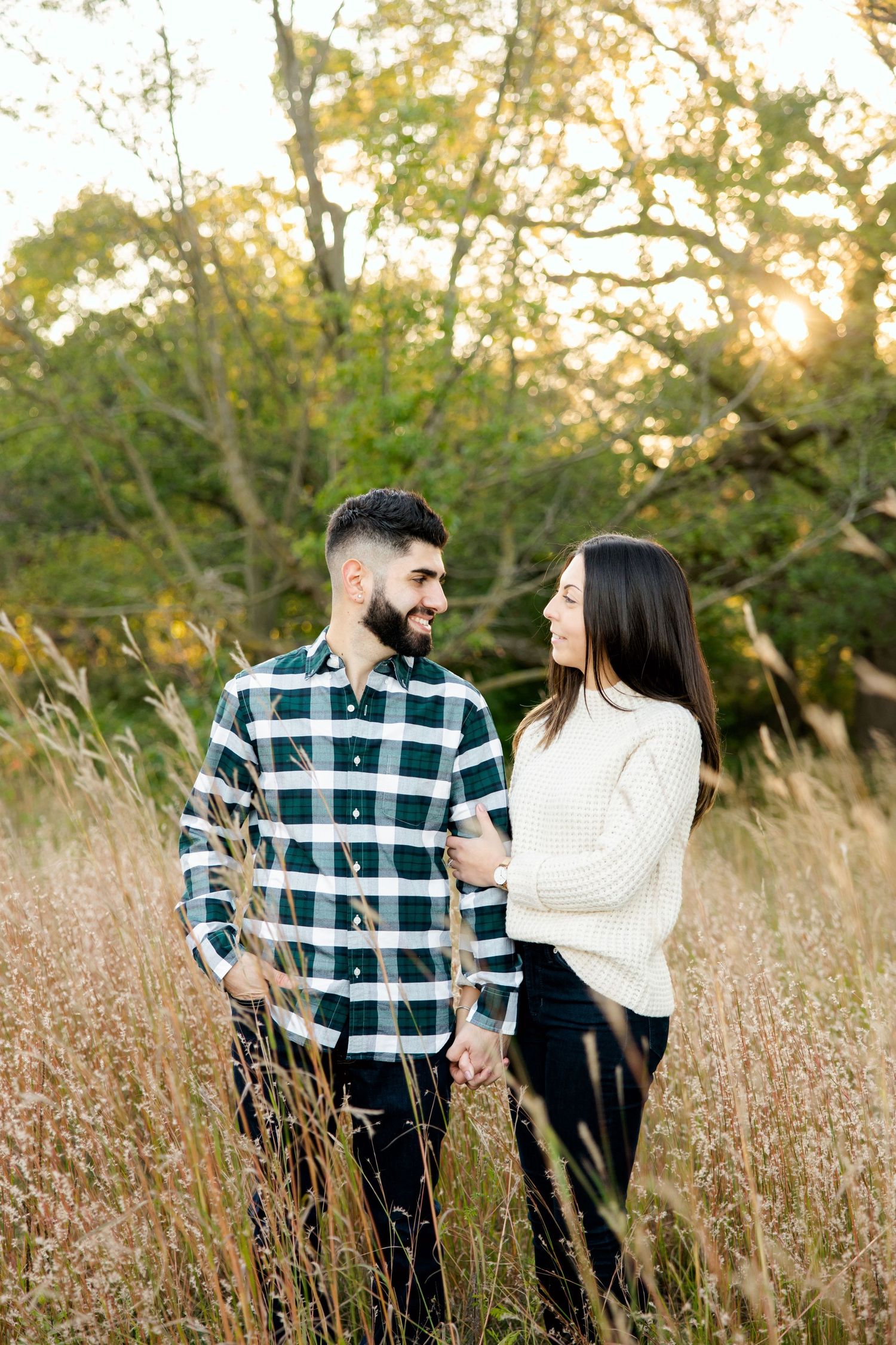 Couple shares loving moment in autumn field wearing coordinated casual outfits.