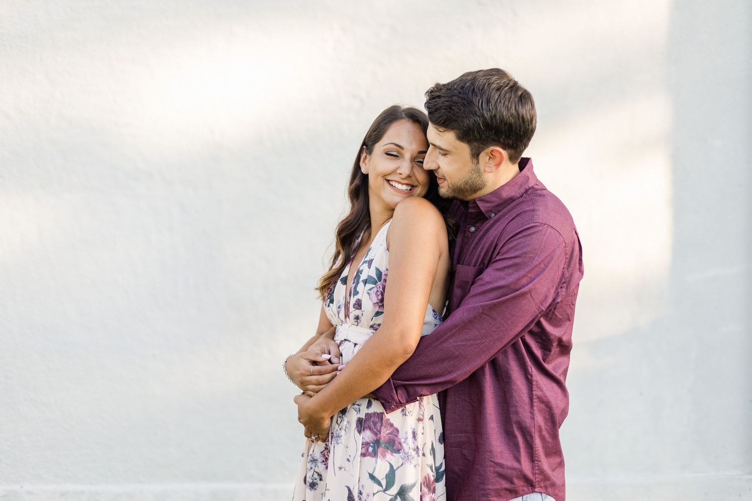 Couple shares an intimate embrace while wearing coordinated burgundy and floral outfits.