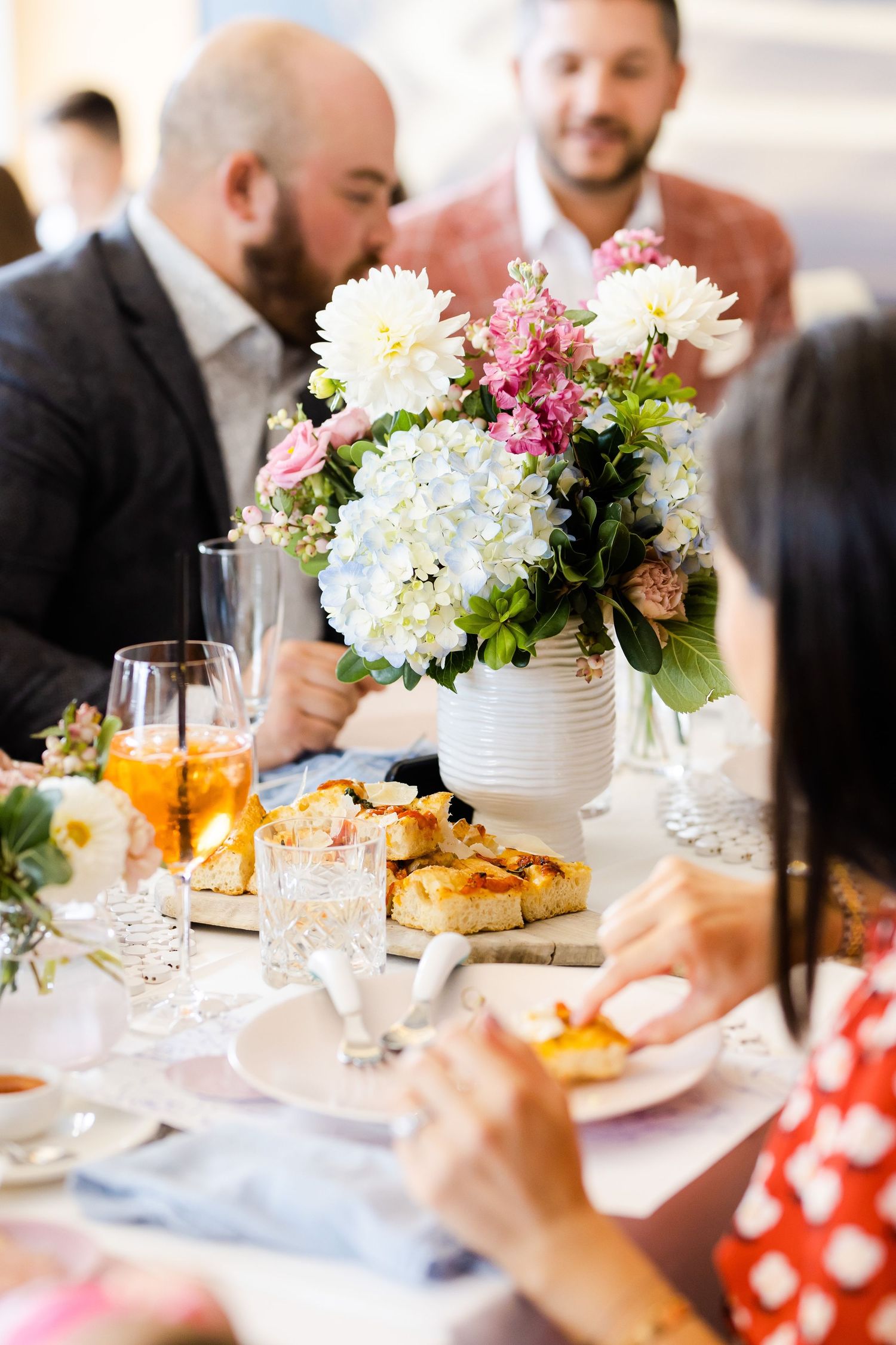 An elegant table setting with white and pink hydrangea centerpiece and brunch plates.