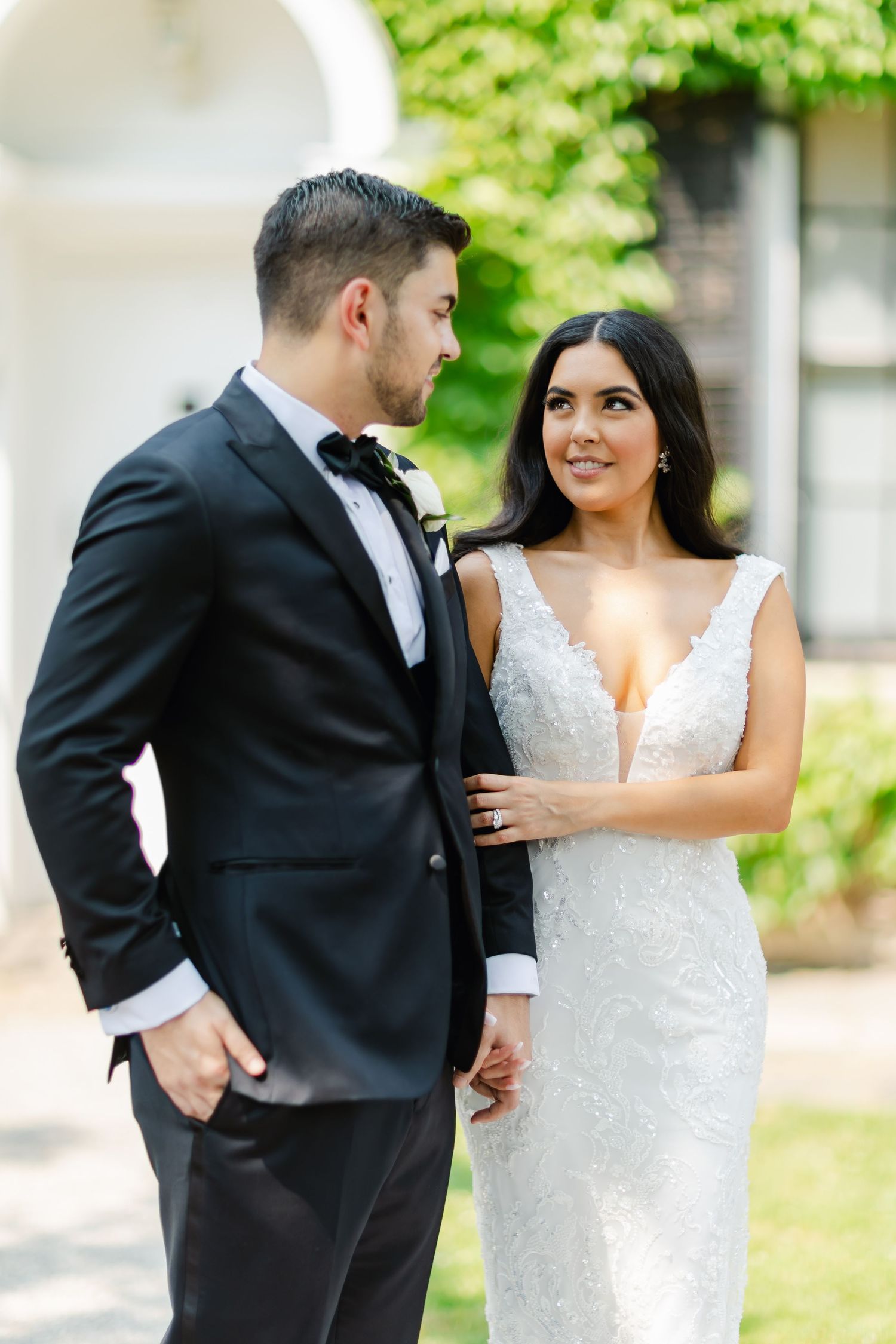 A couple in wedding attire poses together against an ivy-covered building on their special day.