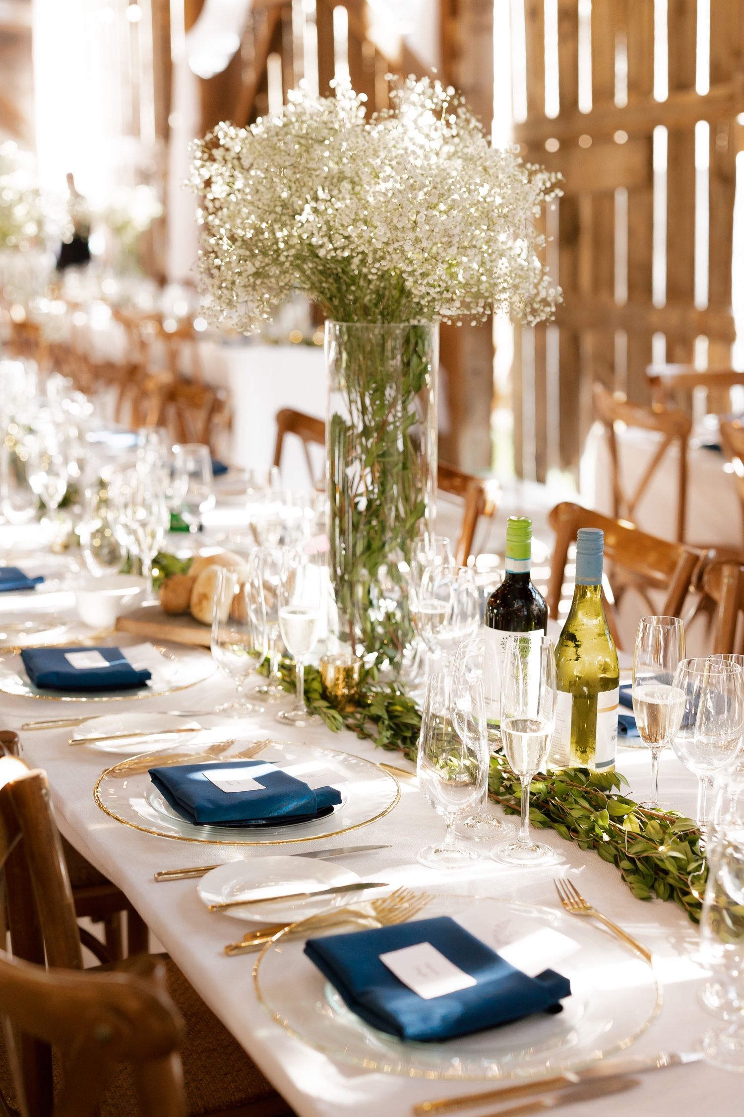 A wedding table setting with navy napkins, baby's breath centerpieces, and elegant glassware.