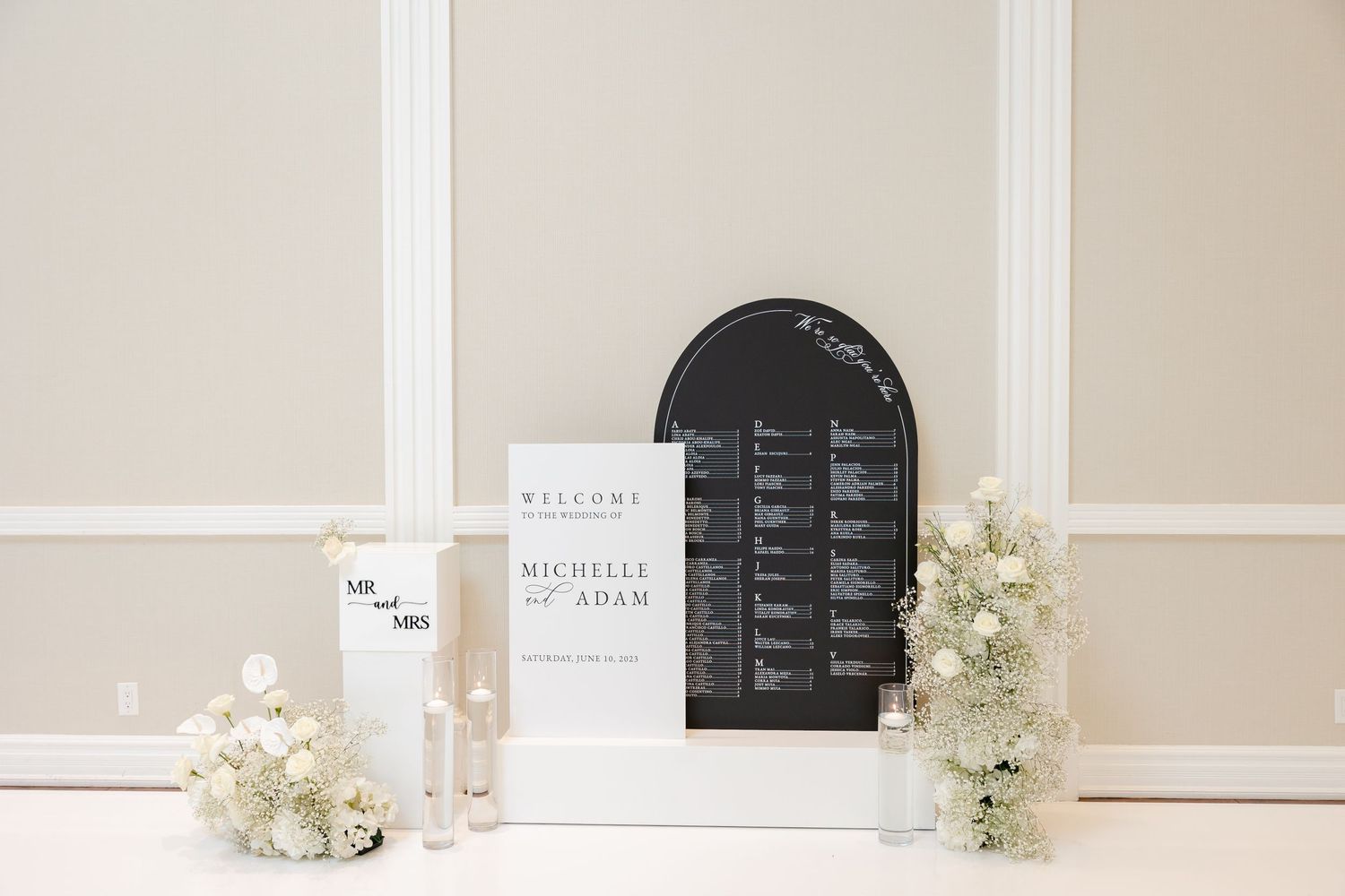 Clean wedding display setup with seating chart and white floral arrangements.