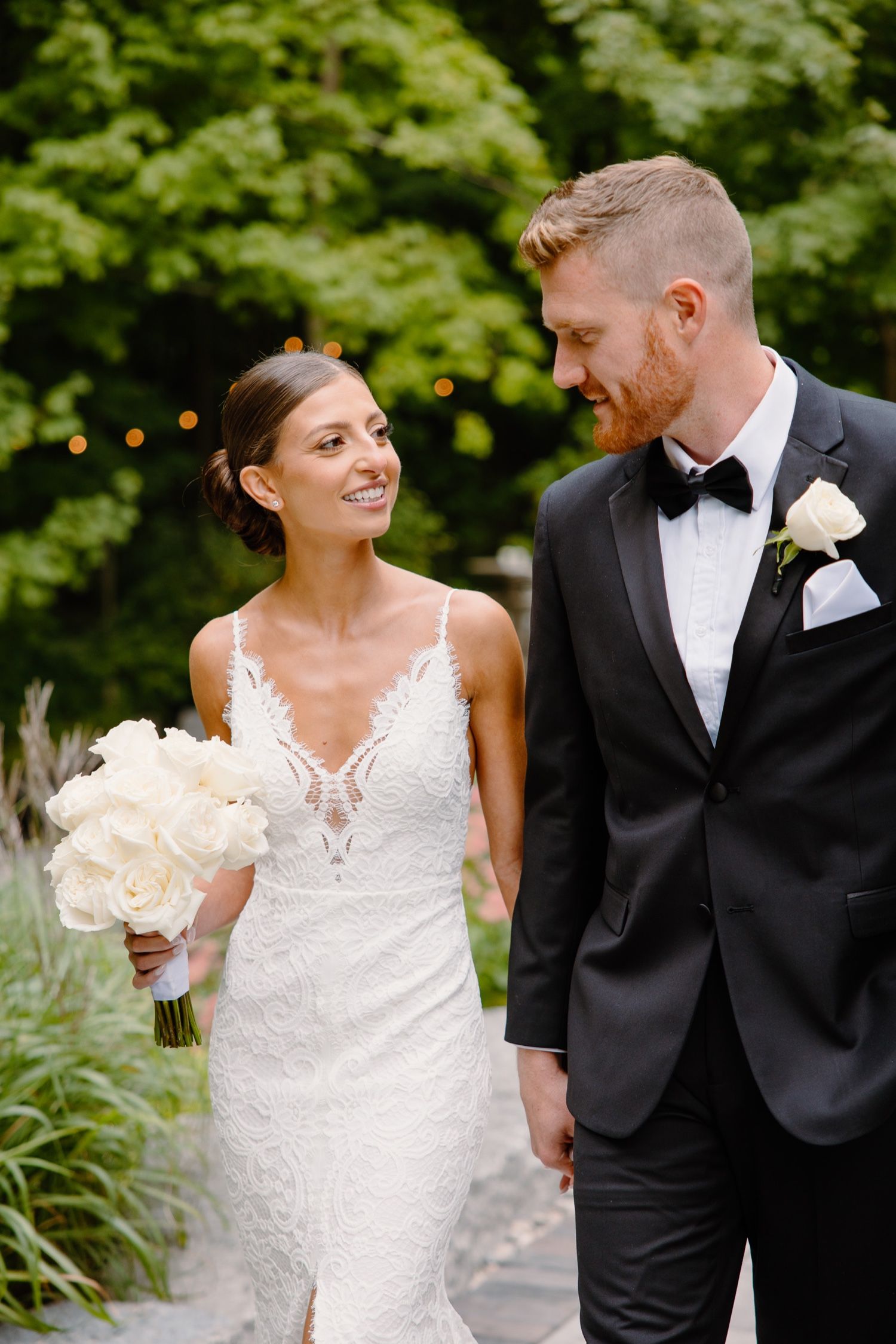 An intimate moment captured between a couple in formal wedding attire with white floral bouquet.