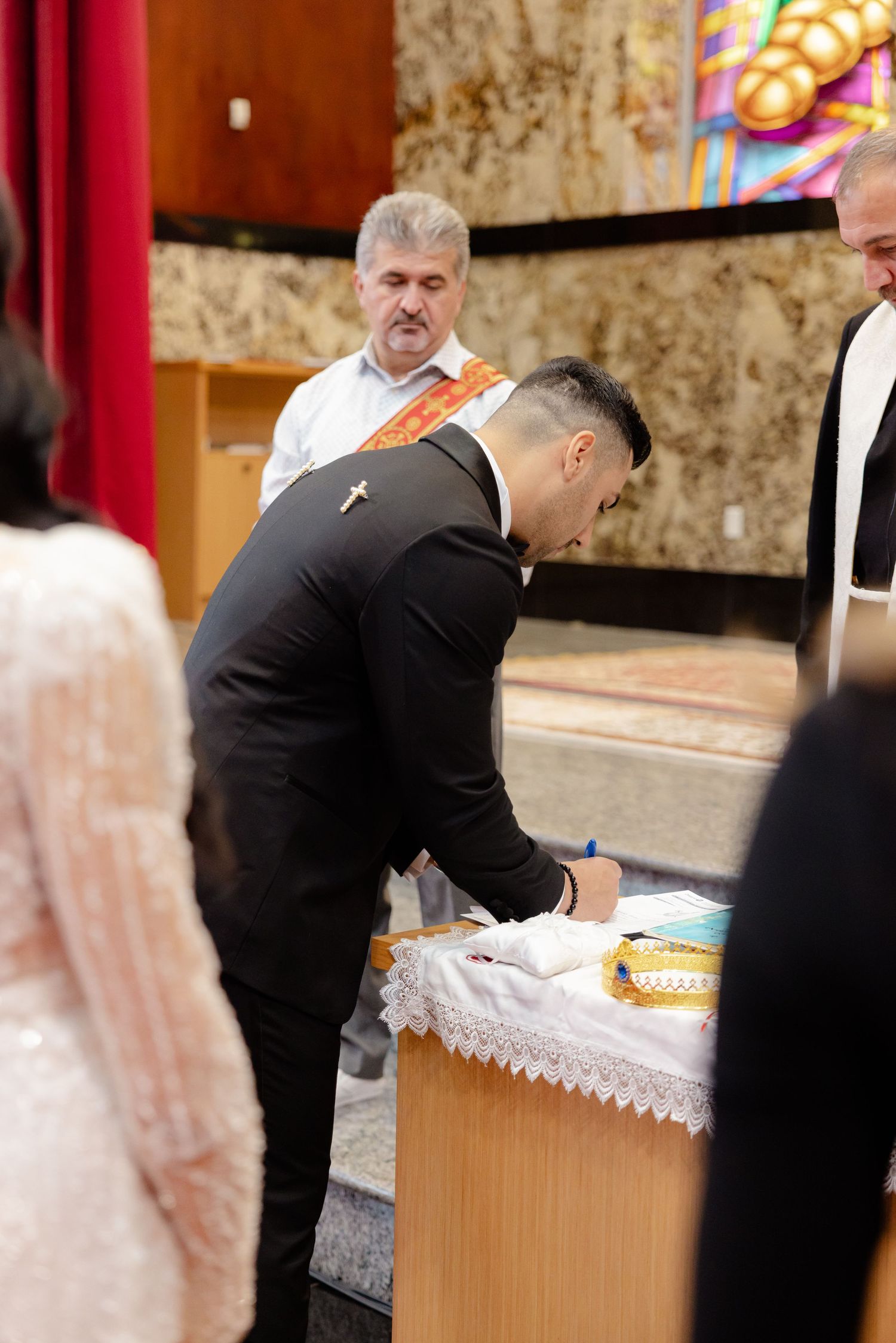 A wedding ceremony participant signs documents at a table during the service.