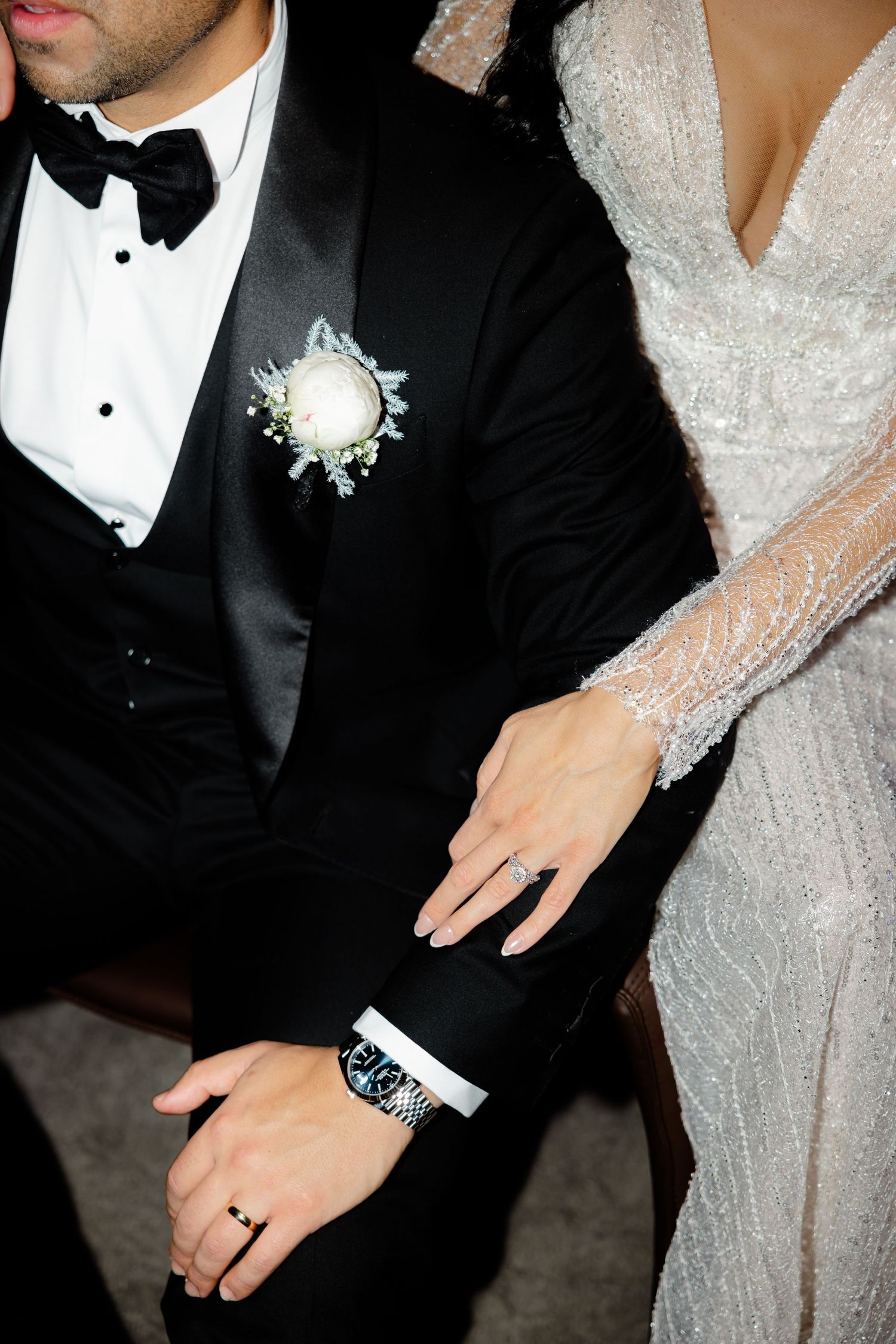 Close-up of wedding couple showing formal attire details and white boutonniere.