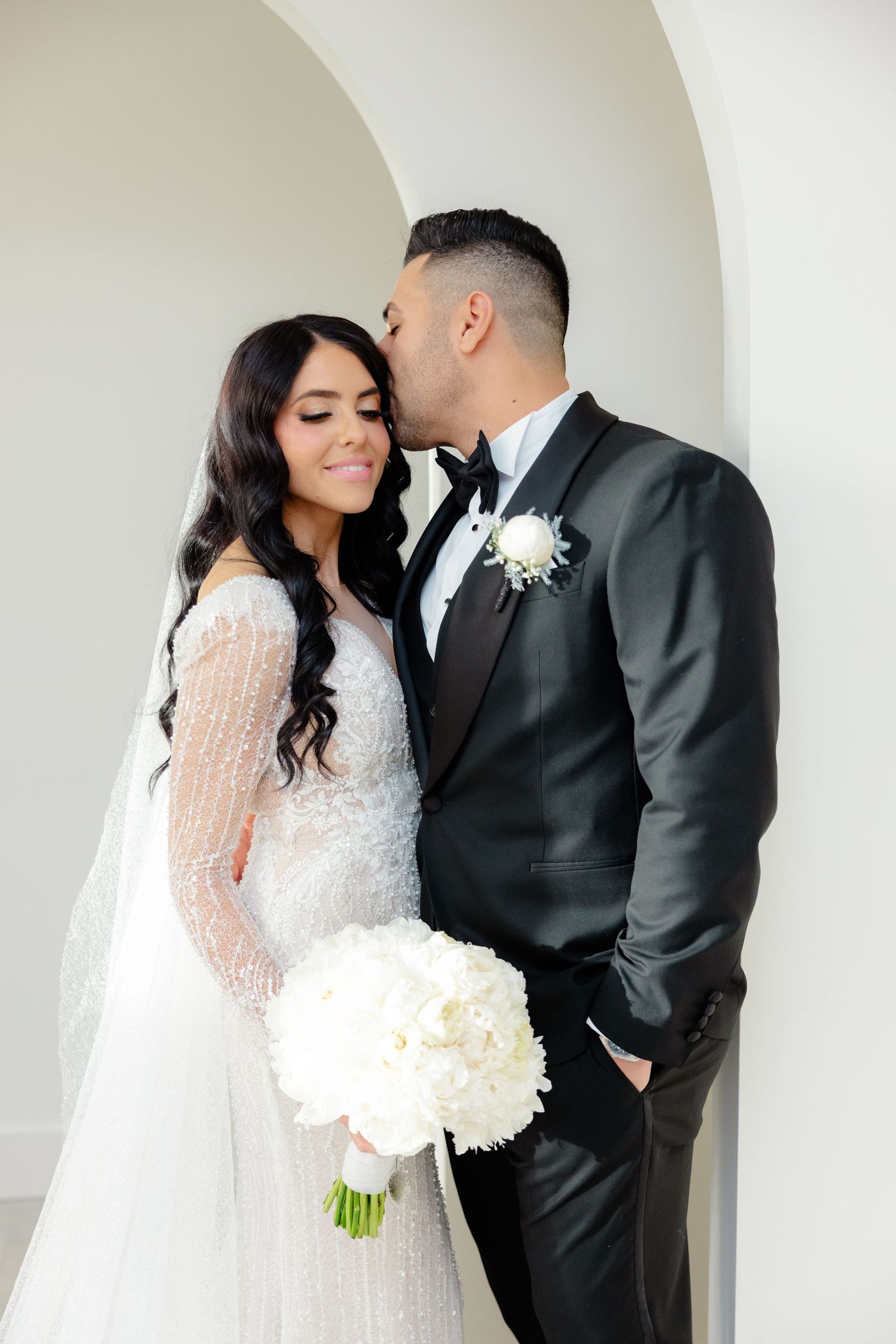 Intimate wedding moment captured with couple under architectural archway.