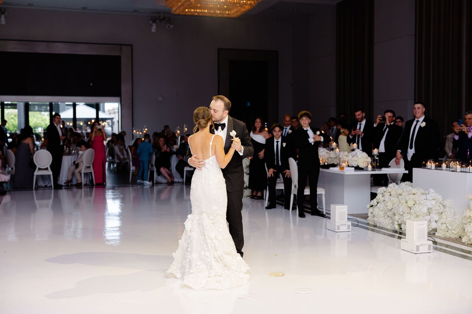 Elegant couples glide gracefully across a spacious ballroom dance floor during a formal reception event.