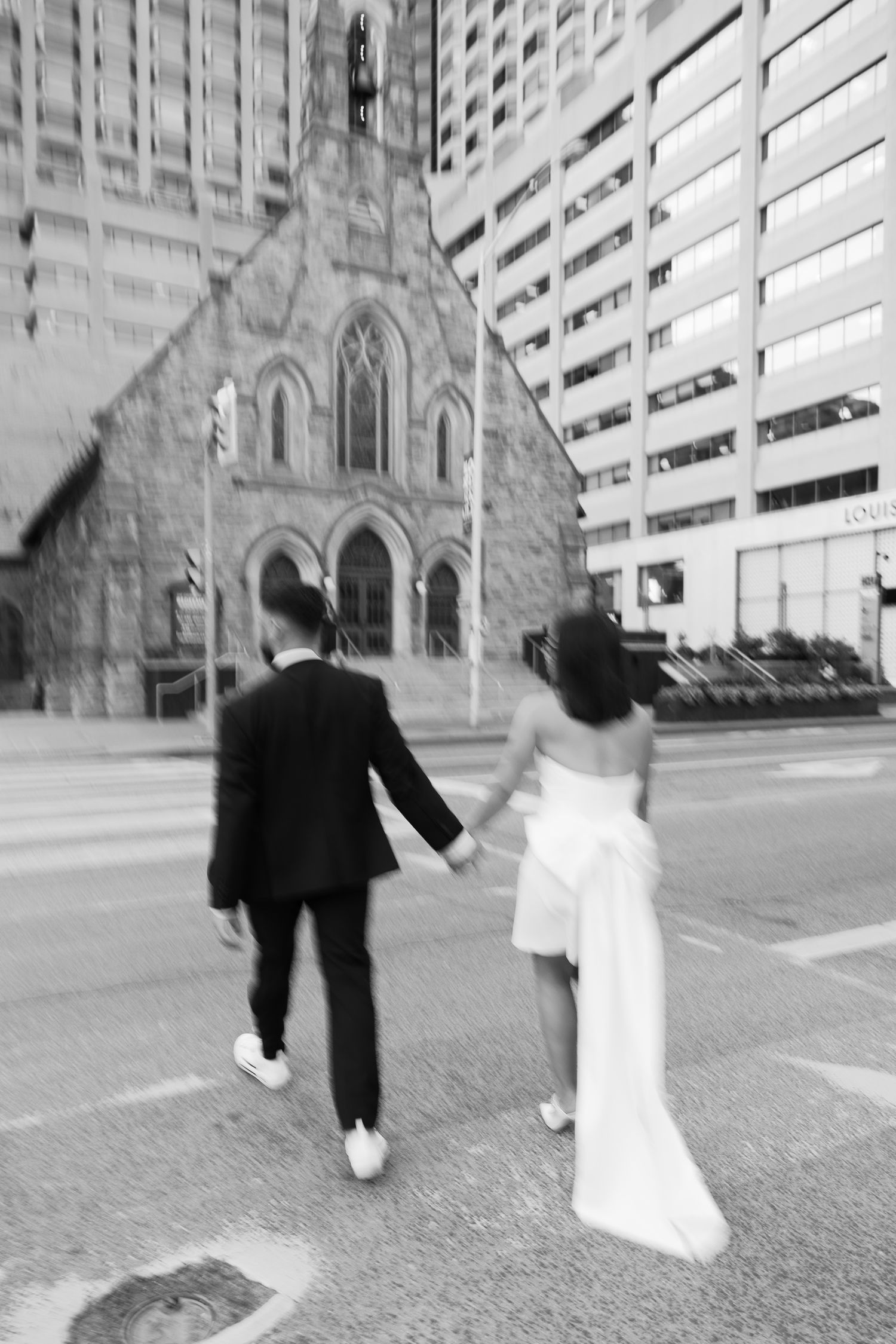 Couple walking hand in hand towards historic church building in urban setting.