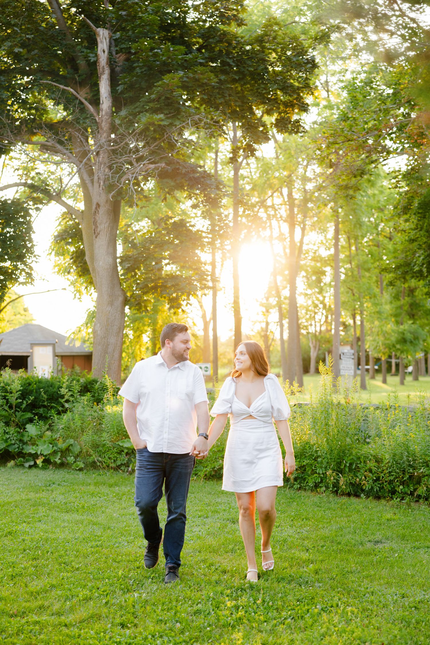 Couple takes romantic walk through garden path during golden hour.