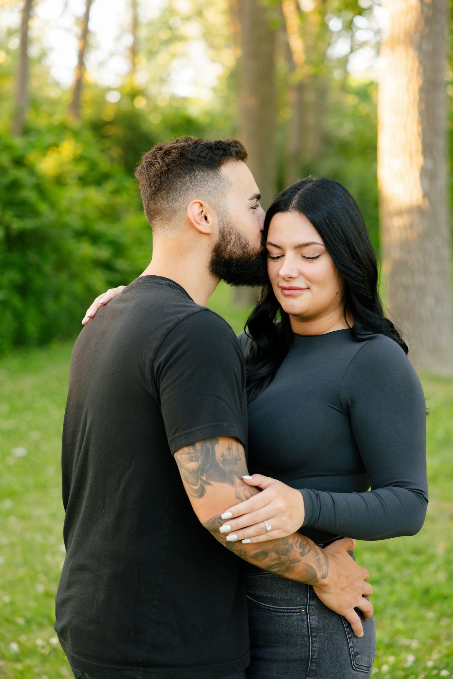 Intimate portrait of couple embracing in a serene forest setting during golden hour.