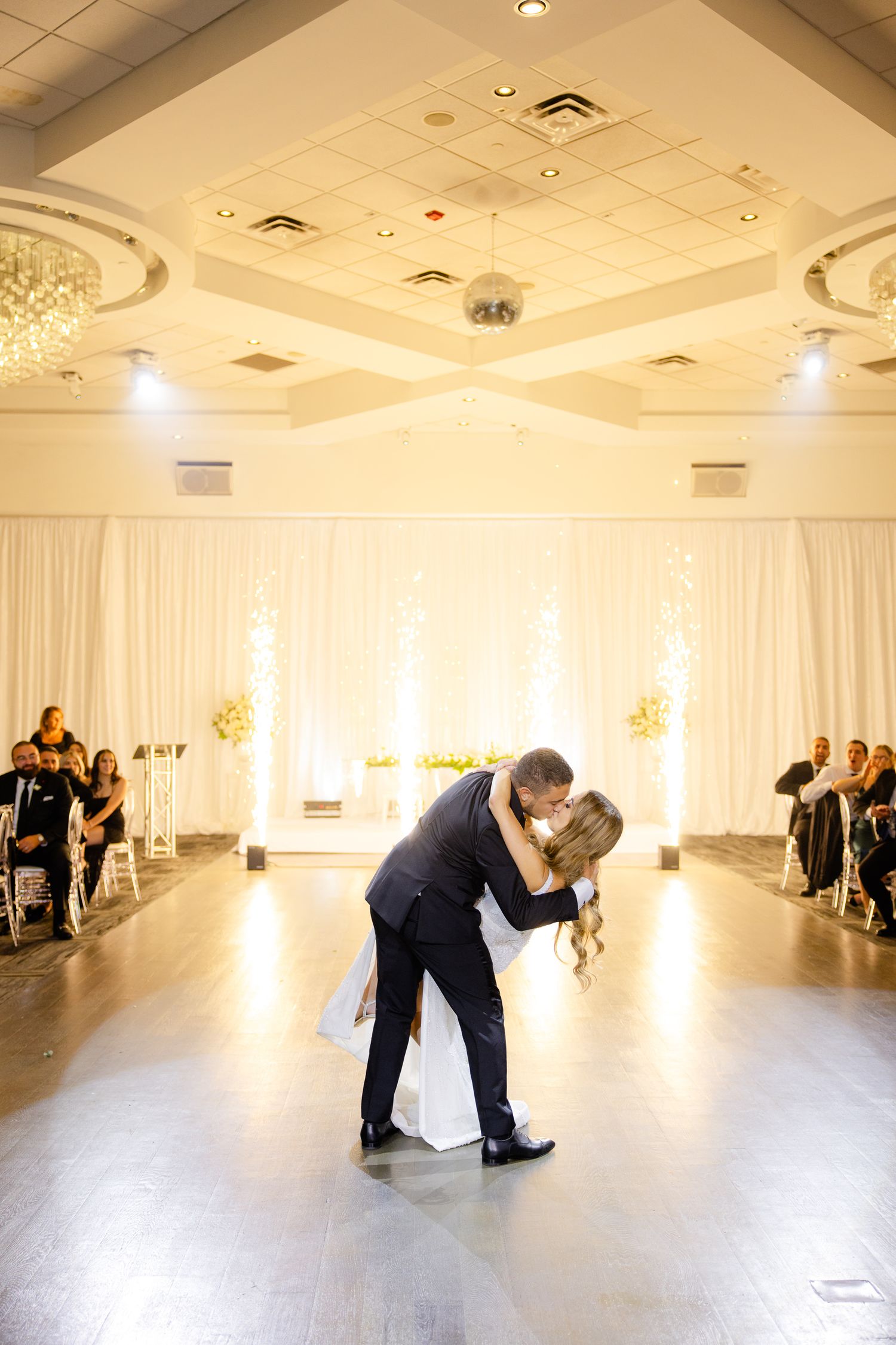Intimate dance moment captured in a luxurious ballroom setting with ornate ceiling details.