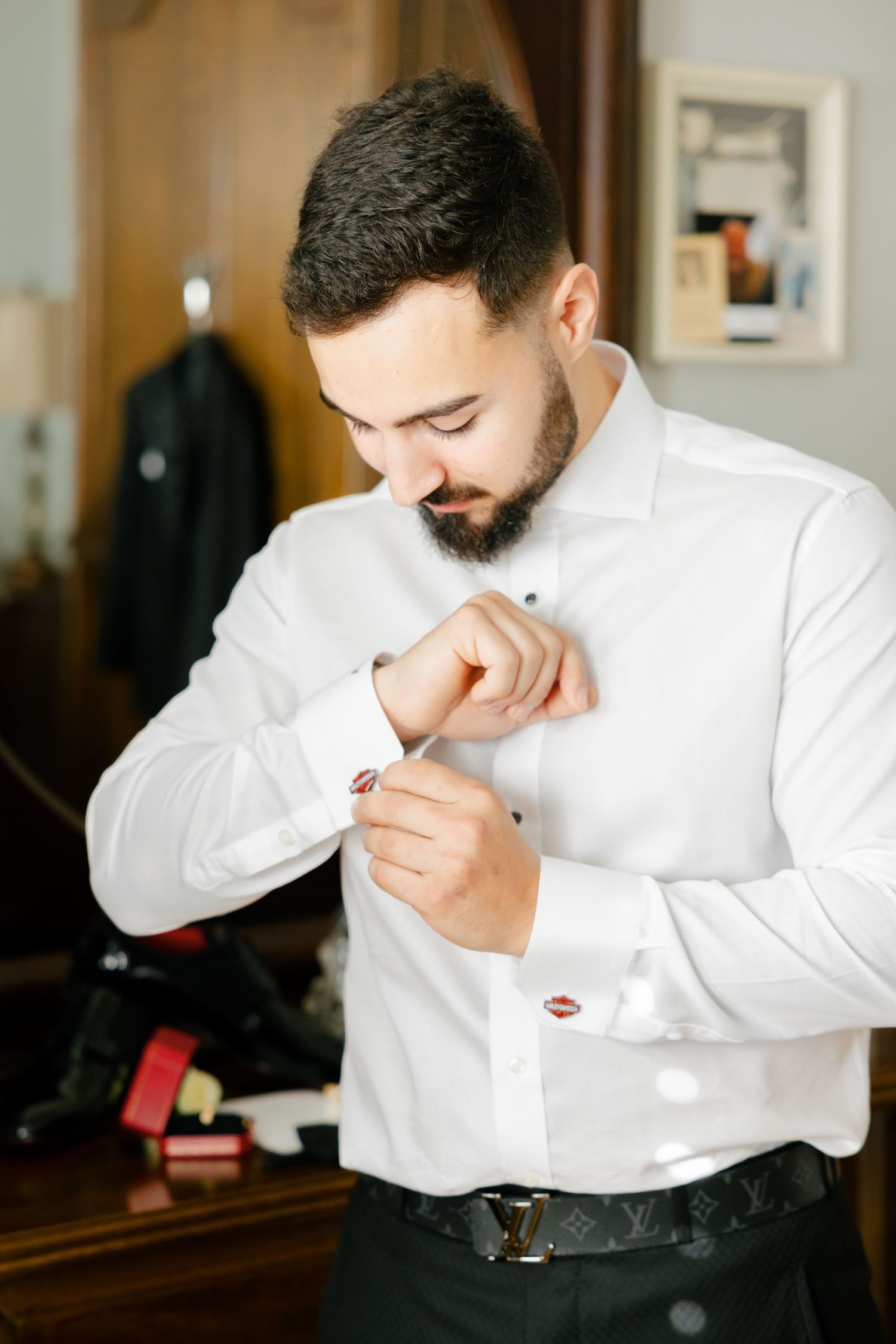 Person in white dress shirt adjusting cufflinks while getting ready.