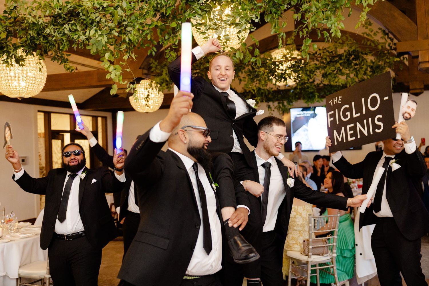 Joyful celebration moment during wedding reception with formal attire and decorative lighting.