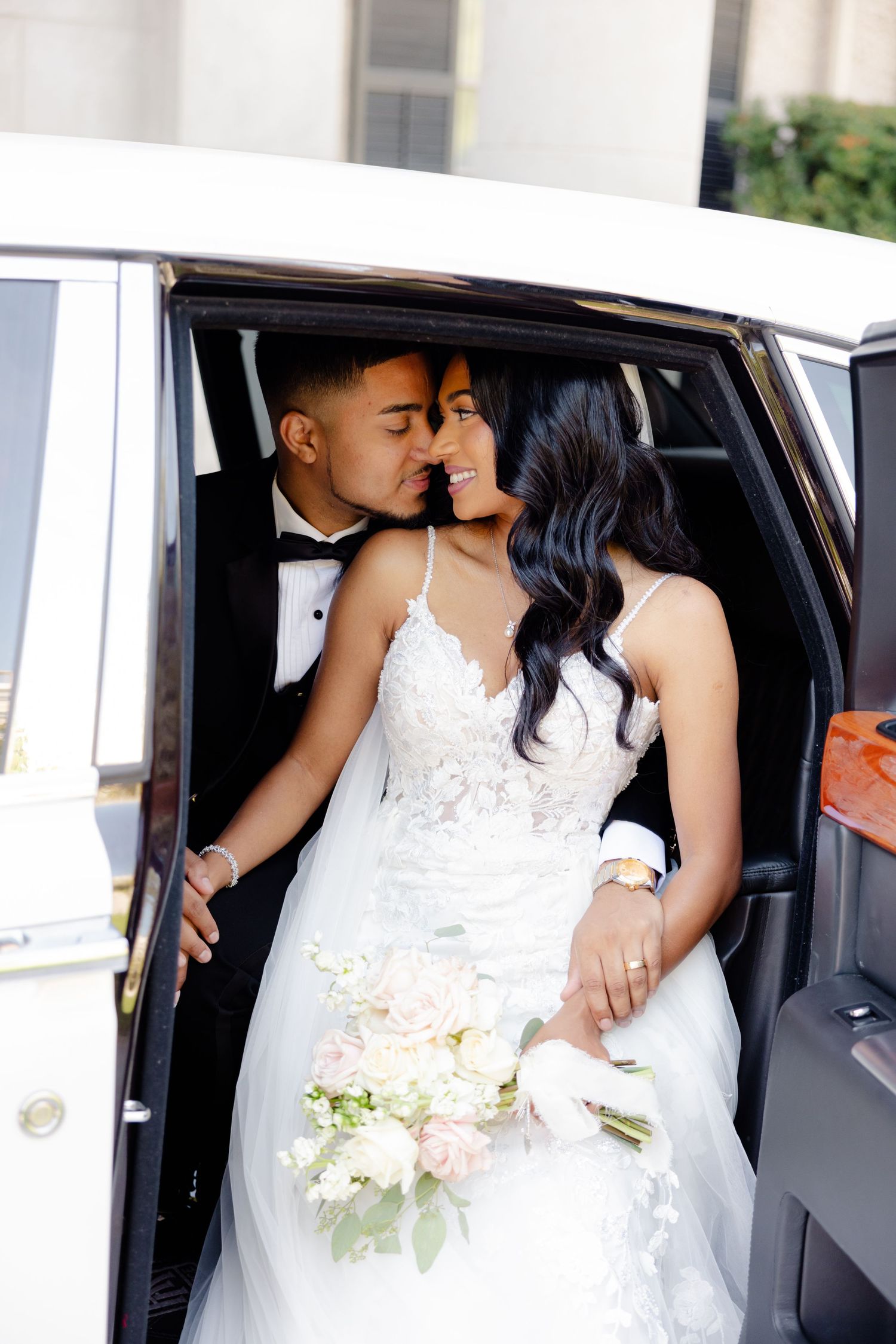 A romantic wedding couple sharing an intimate moment in a luxury car on their special day.