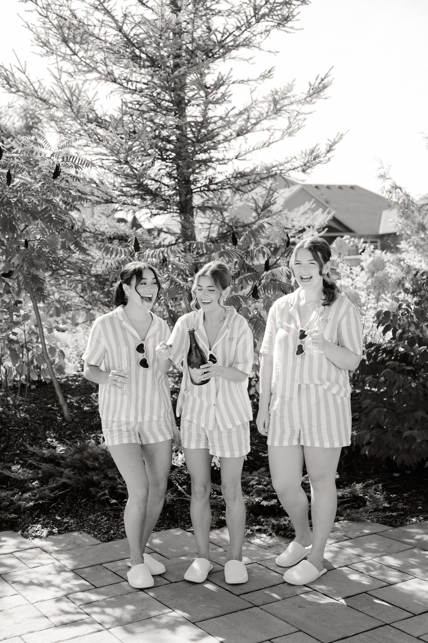 Black and white photo of group in coordinated striped outfits posing outdoors.