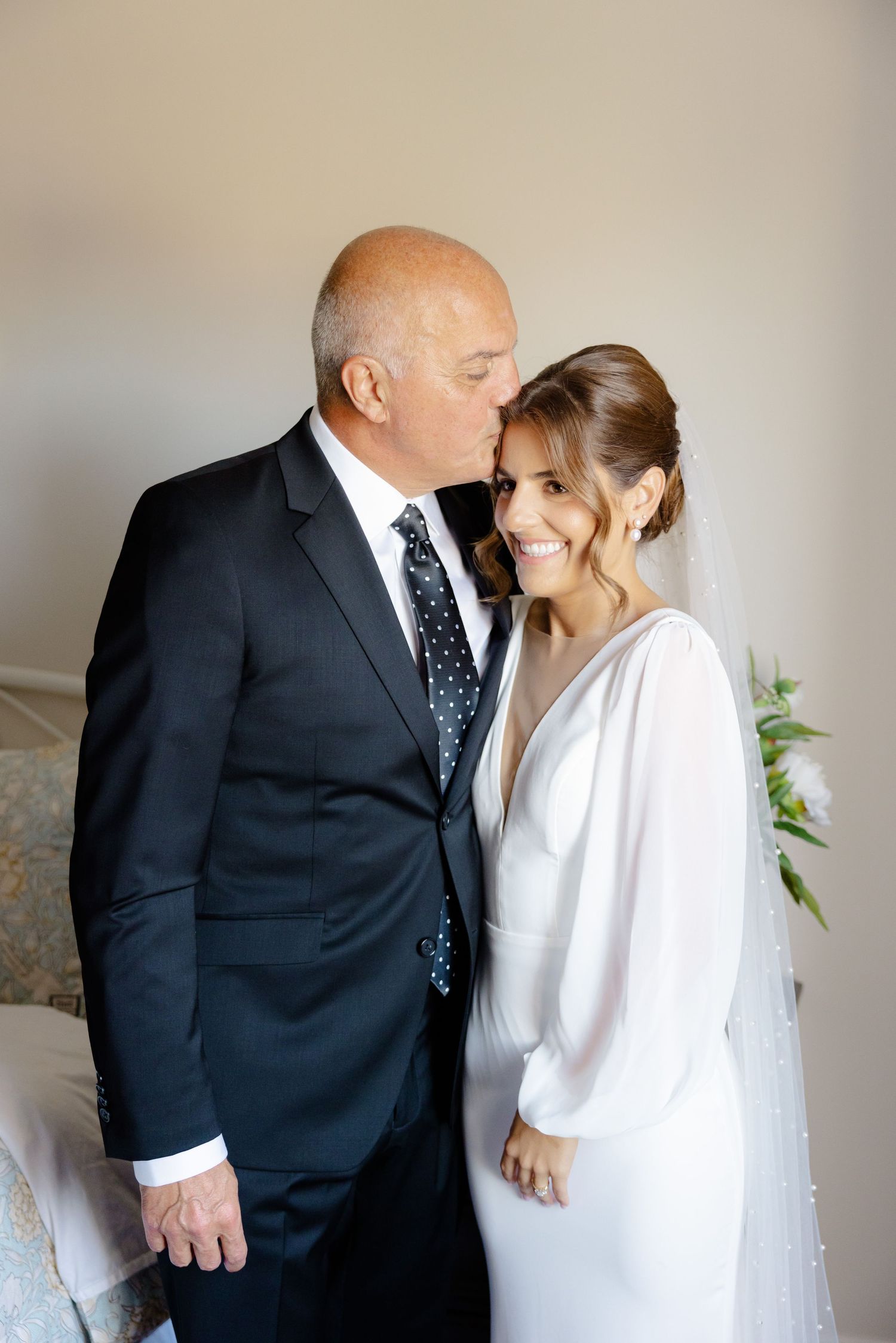 Intimate wedding portrait of a bride in a white gown and groom in a dark suit sharing a tender moment.