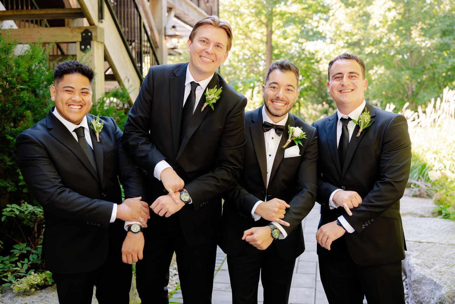 Wedding party members in formal attire share lighthearted moment outdoors.