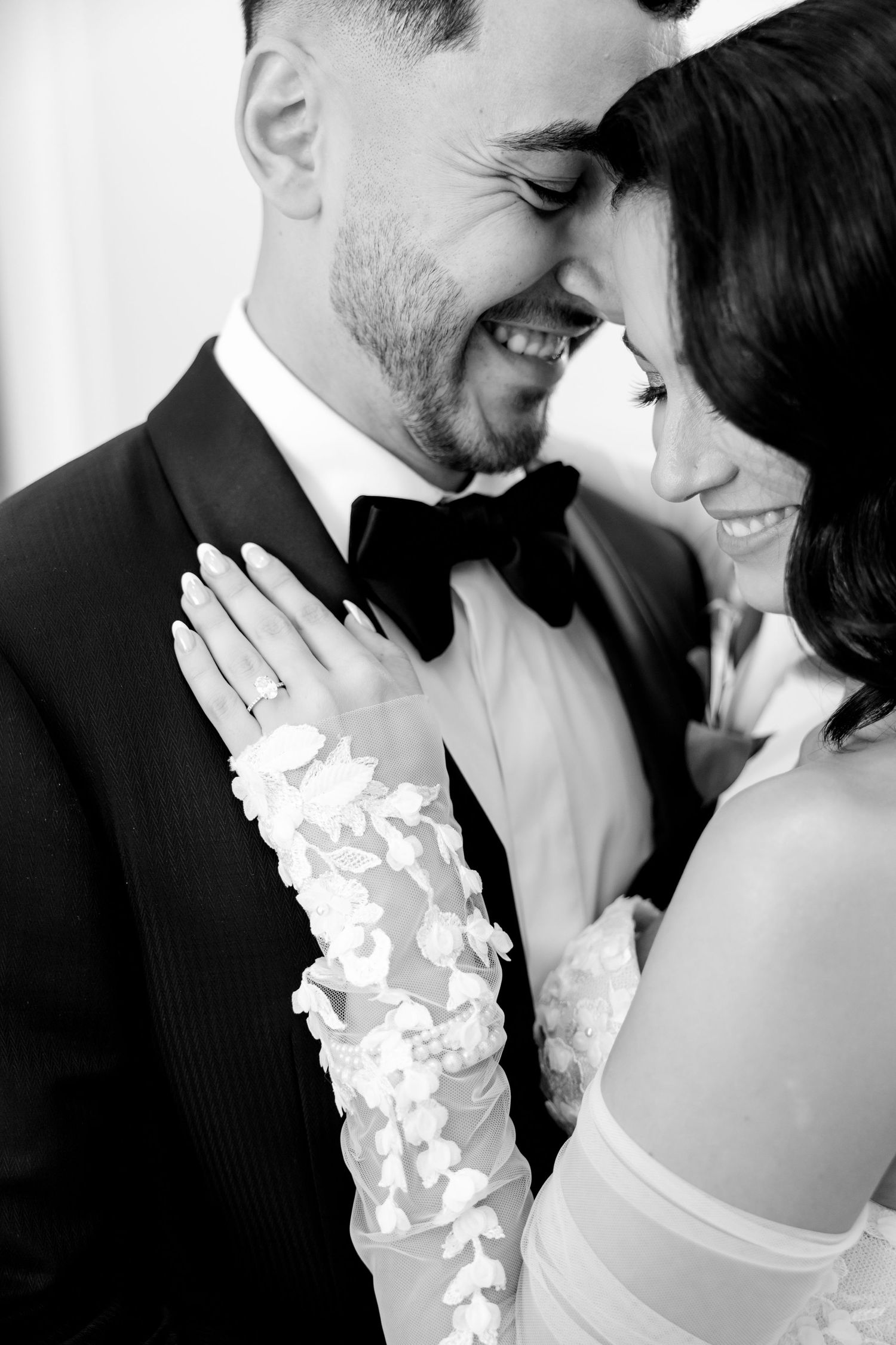 Black and white portrait of newlyweds sharing an intimate laugh during their wedding photoshoot.