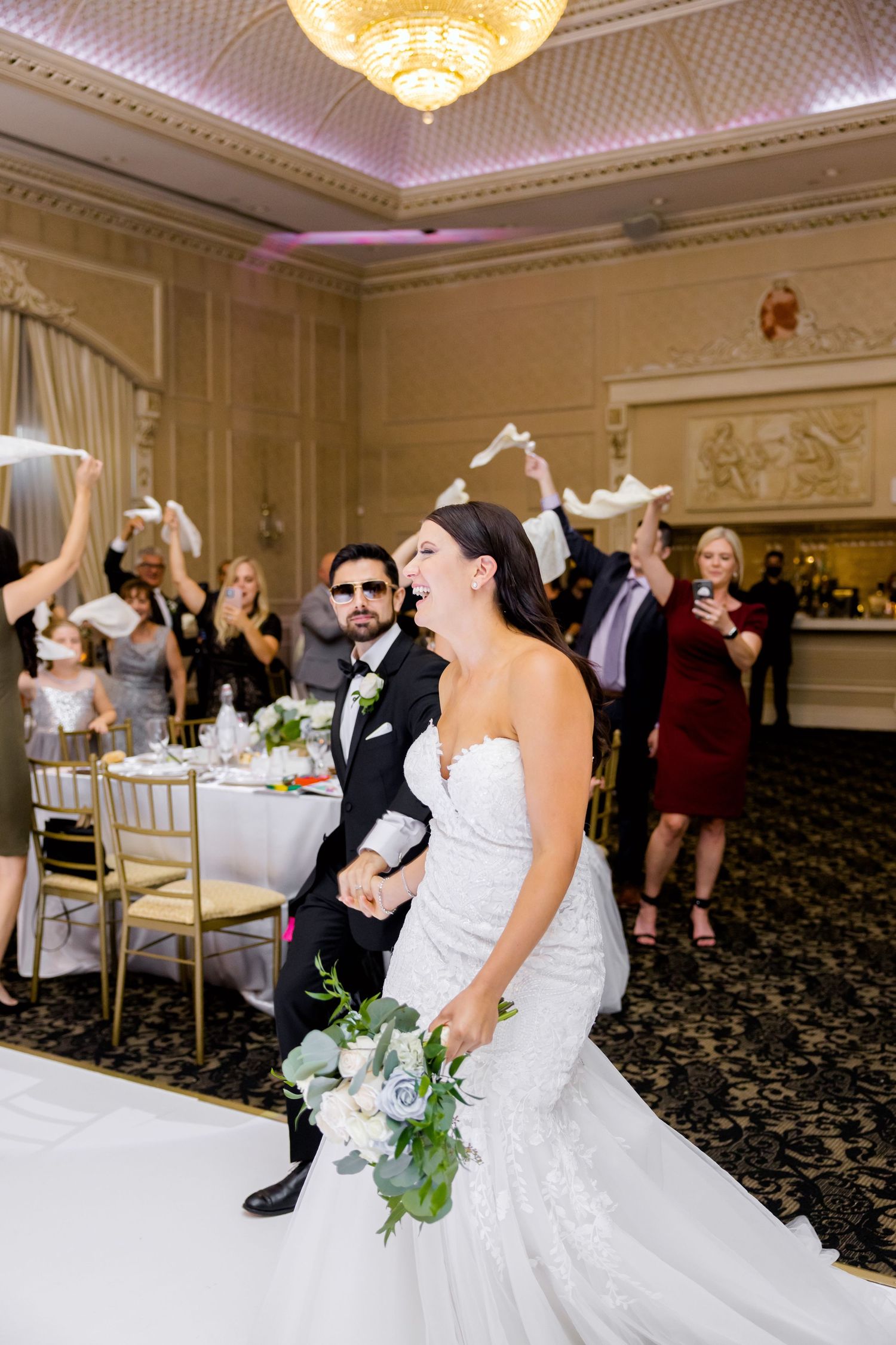 Joyful celebration moment in an elegant ballroom with chandelier and ornate details.