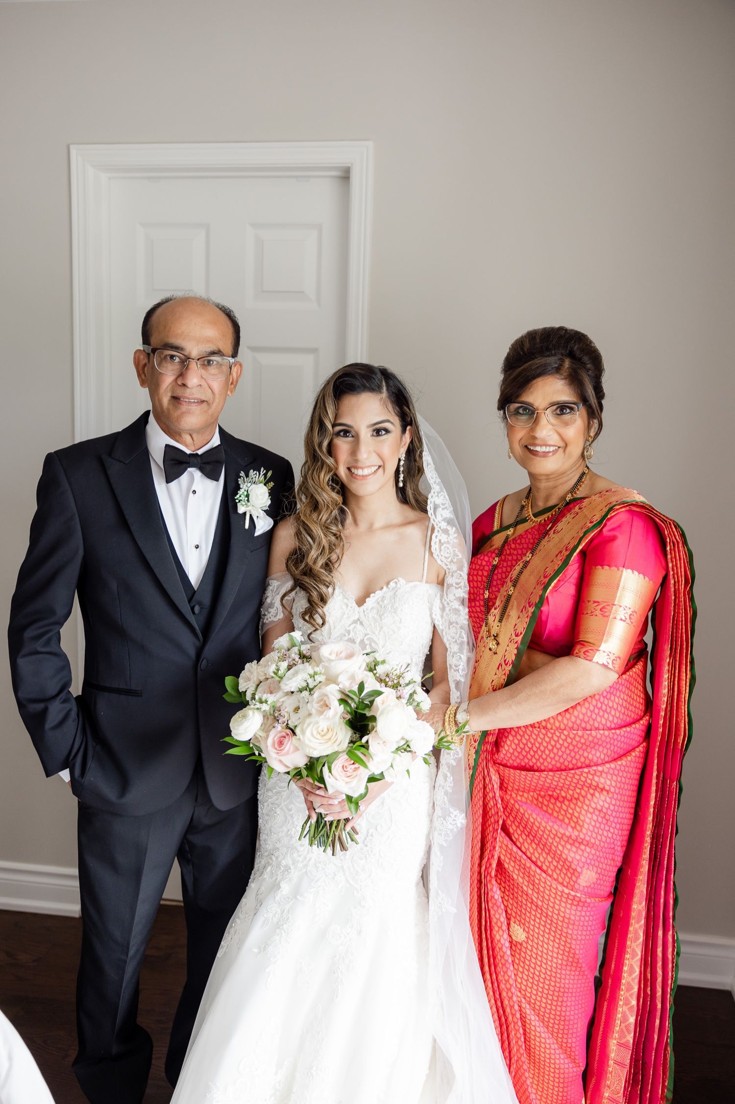 Formal wedding portrait featuring traditional and cultural attire with a white floral bouquet.