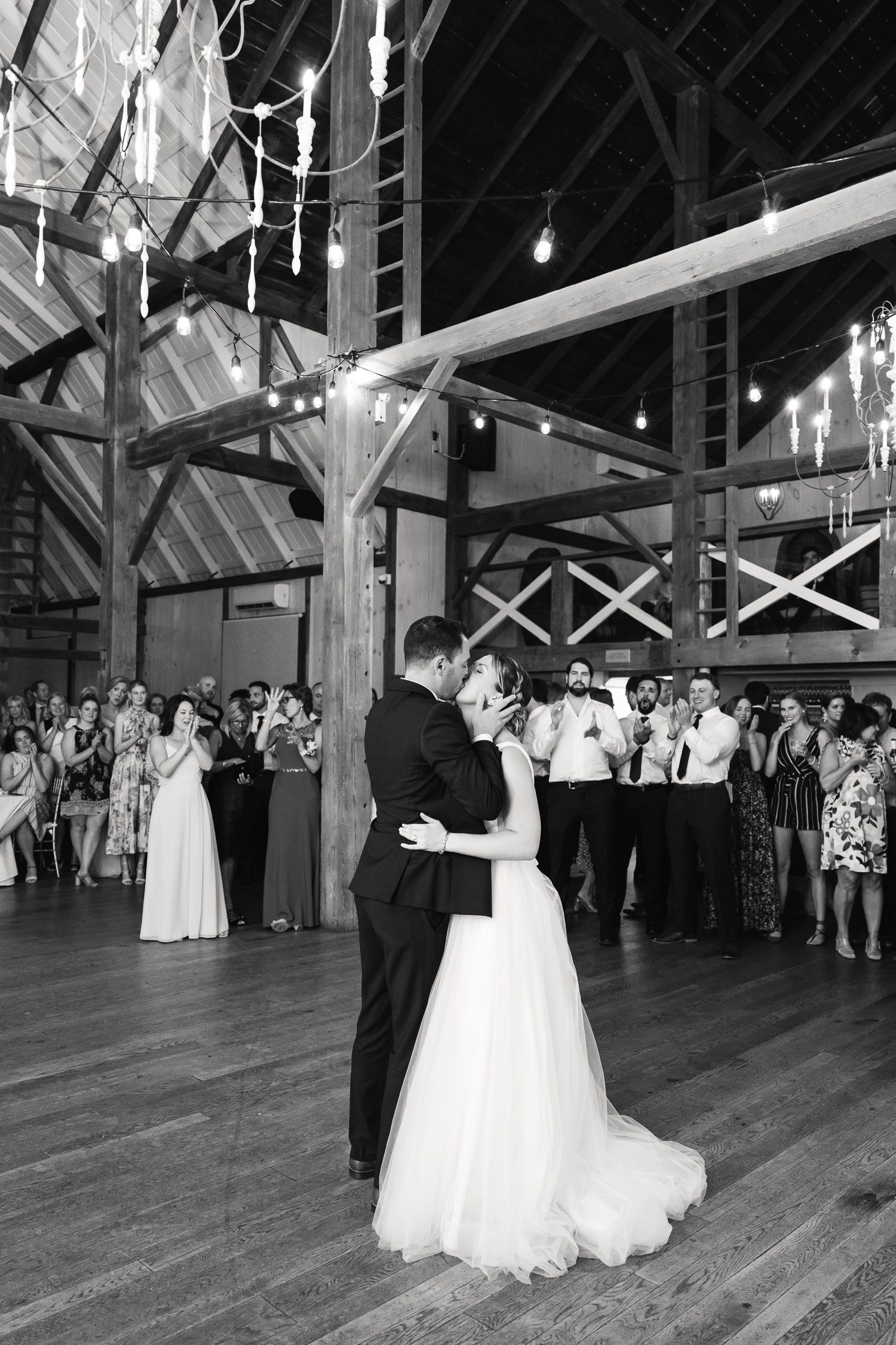 Black and white photo of romantic first dance at rustic barn wedding reception.