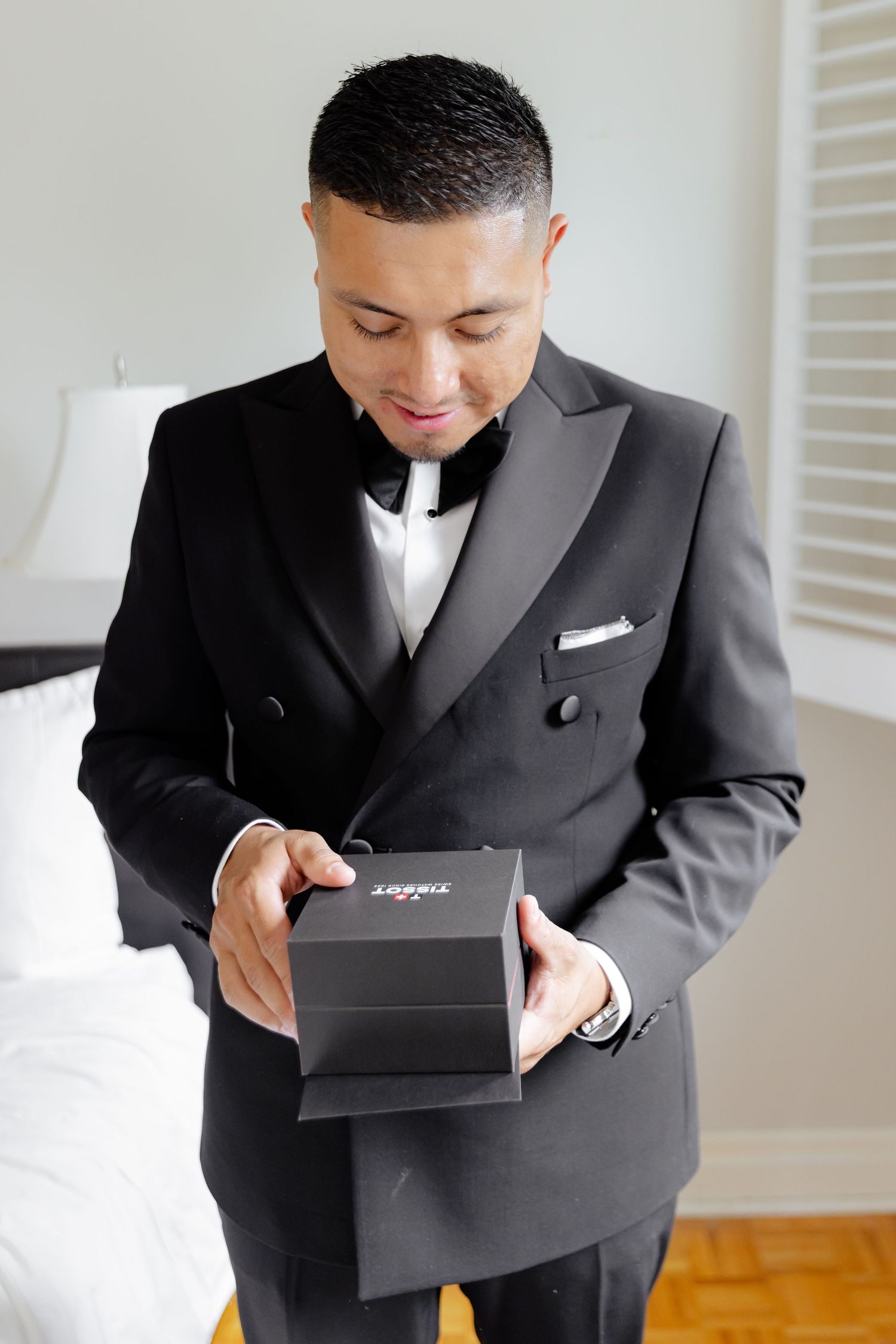Person in black formal suit opens luxurious black gift box while getting ready.