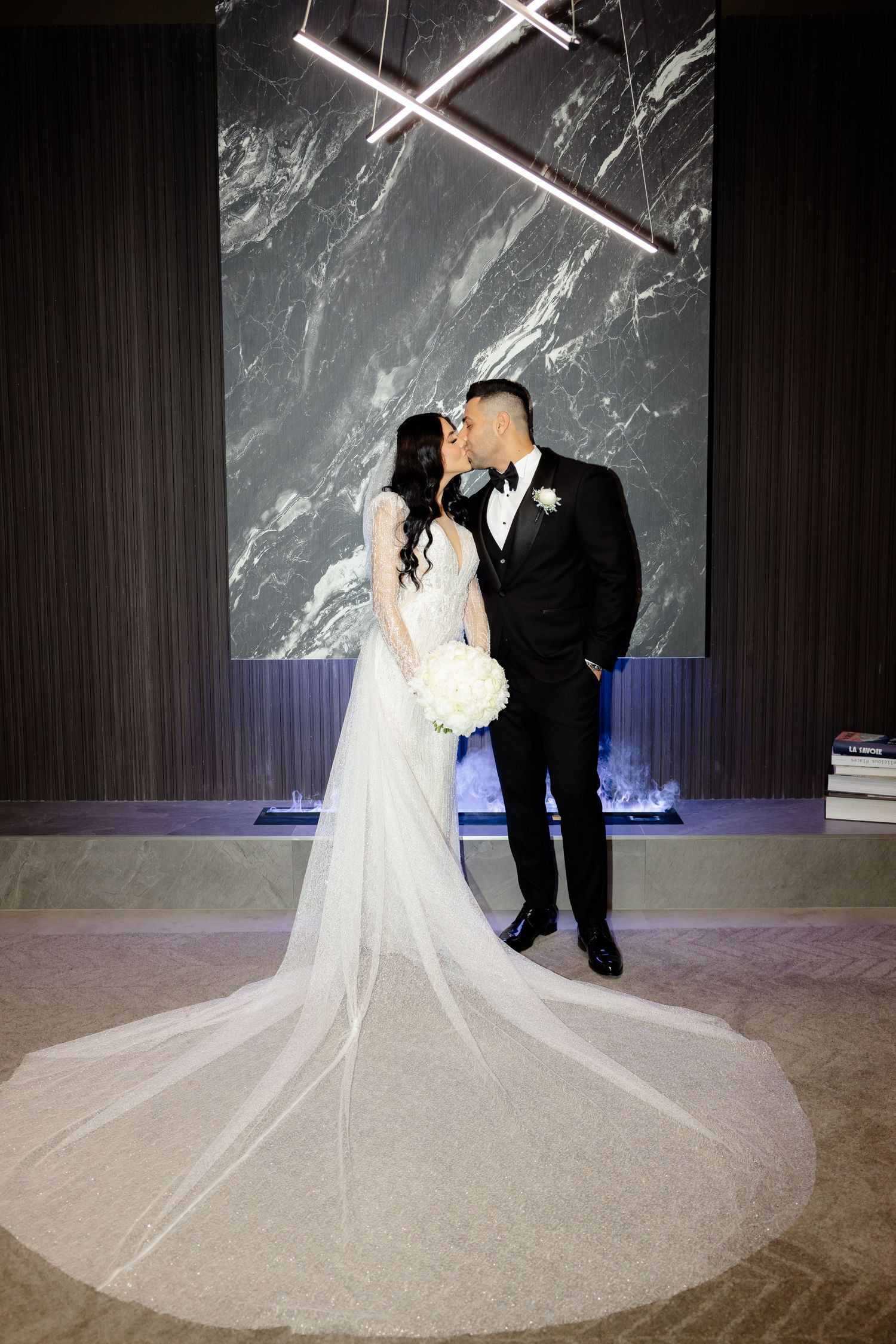 Intimate wedding moment captured with couple against modern marble wall backdrop.