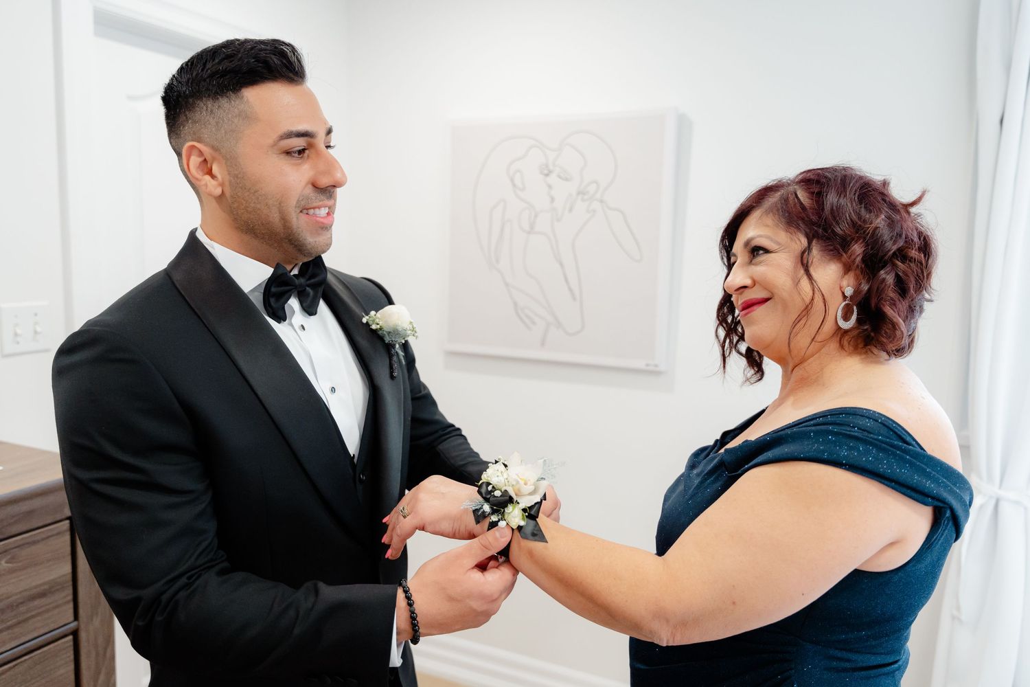 A touching moment shared while pinning on a white boutonniere during wedding preparations.