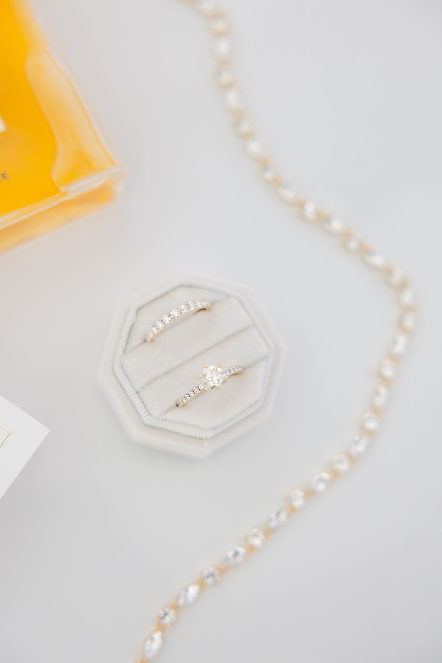 Pearl necklace and wedding rings in octagonal ring box with perfume bottle.