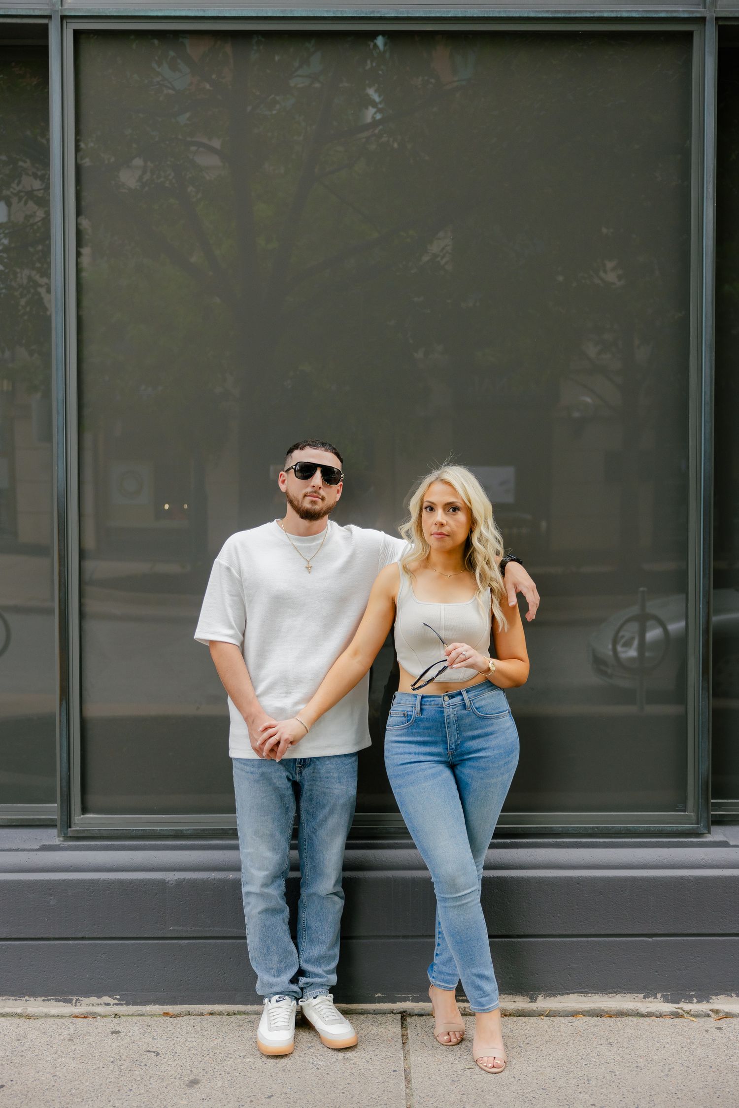 Urban fashion photo of couple in coordinated outfits against dark storefront window.