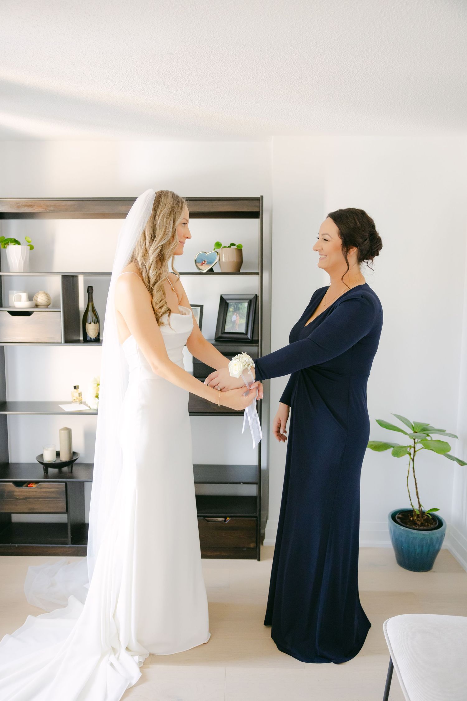 Two people share an intimate moment while preparing for a wedding in a bright indoor setting.