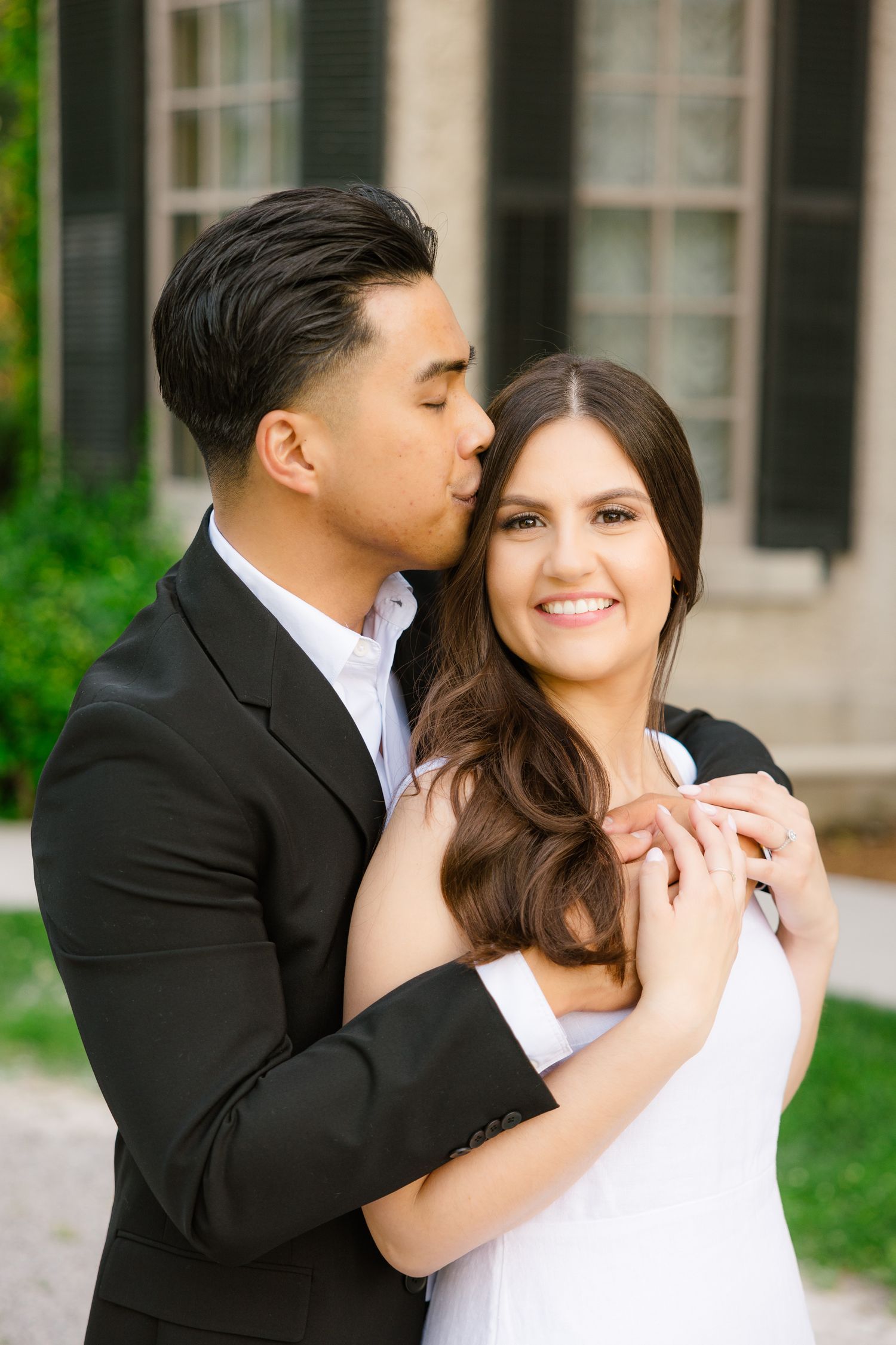 Happy couple in wedding attire embraces in front of classic architecture.