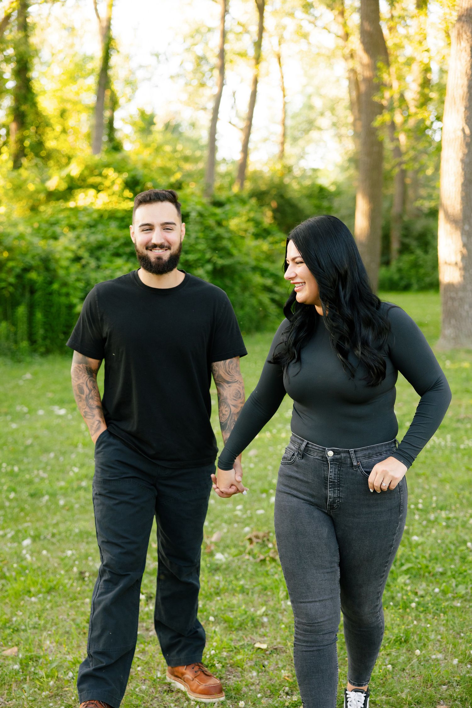 A couple shares a lighthearted moment together in a sun-dappled park.