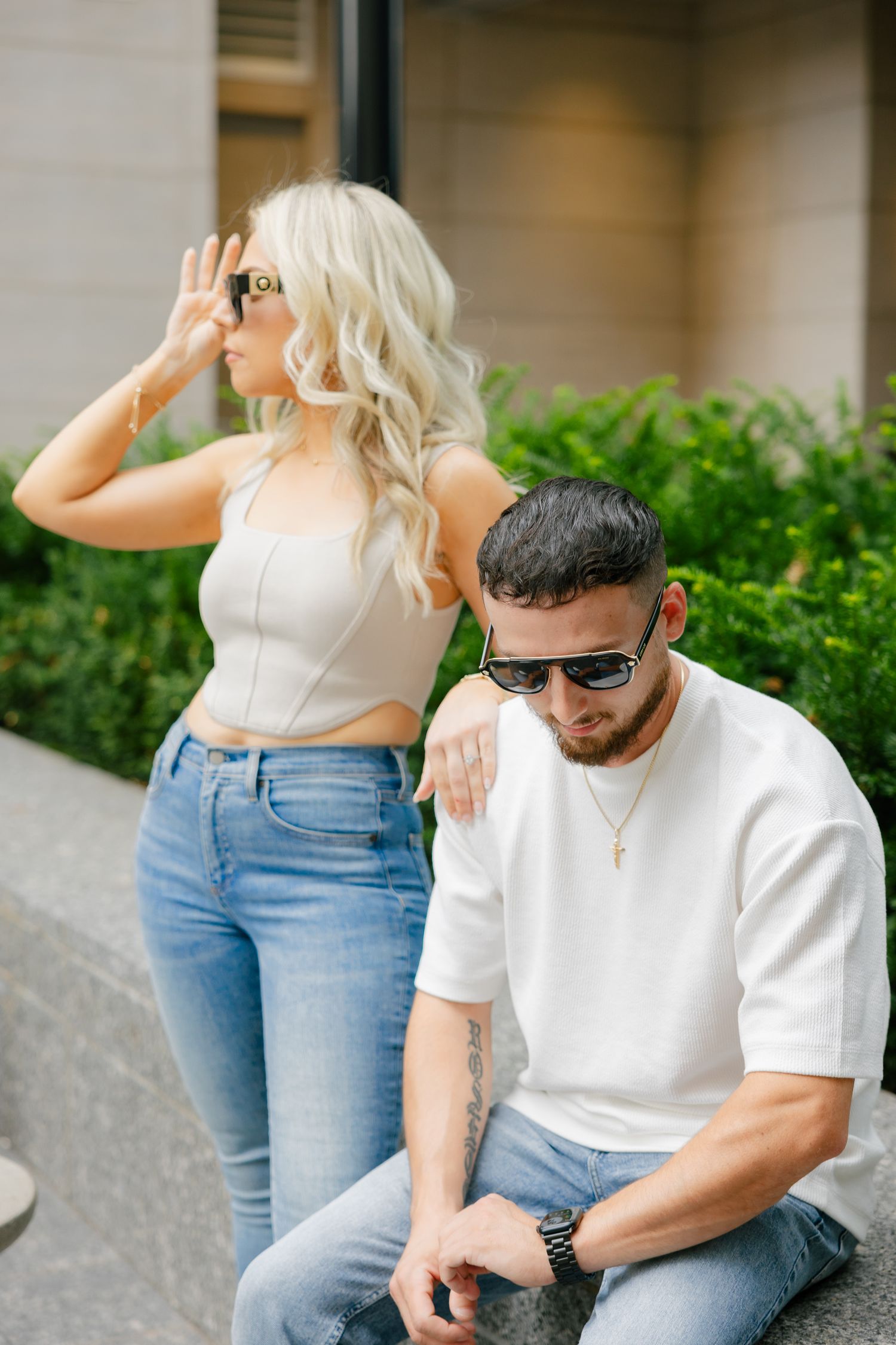 Casual summer photoshoot of couple in coordinated outfits by modern architecture.