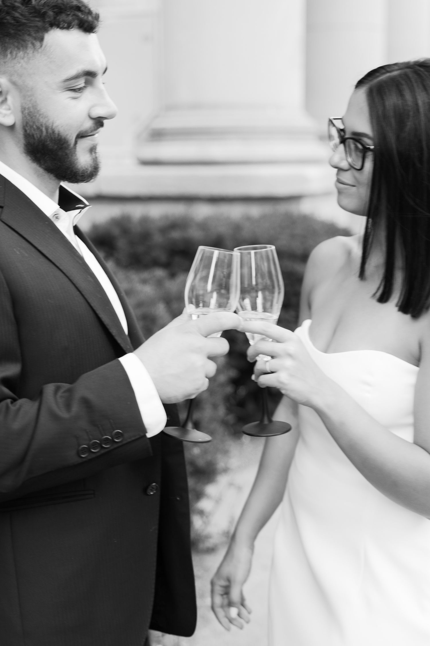 Black and white portrait of couple toasting with wine glasses at formal event.