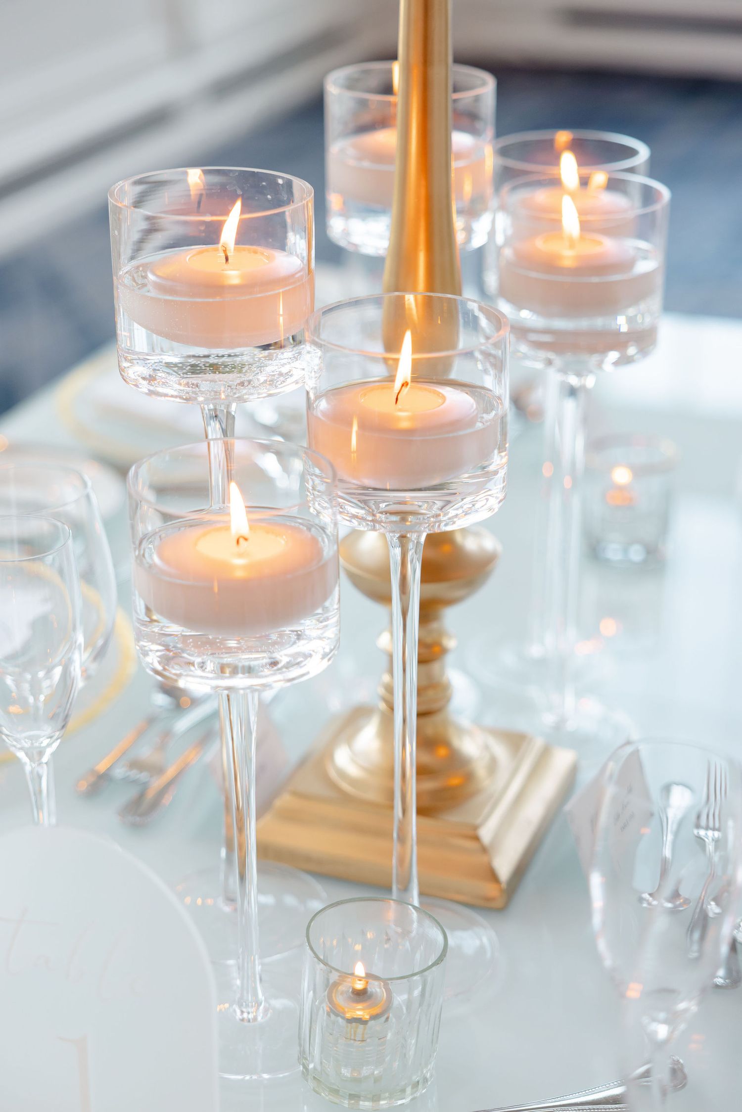 Elegant table setting with floating candles in glass stemware creating romantic ambiance.