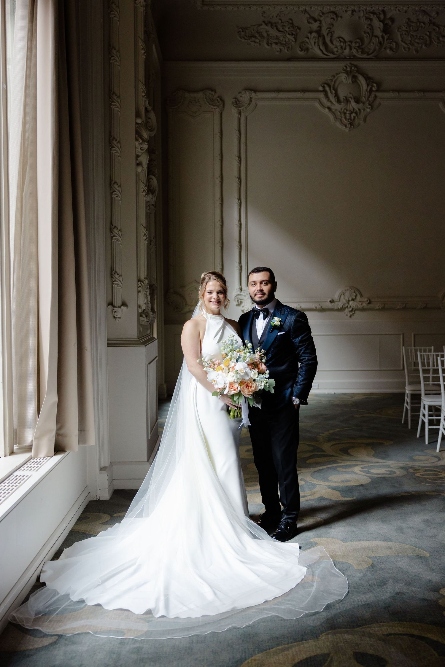 Wedding portraits in an elegant room with ornate moldings and natural window light streaming in.