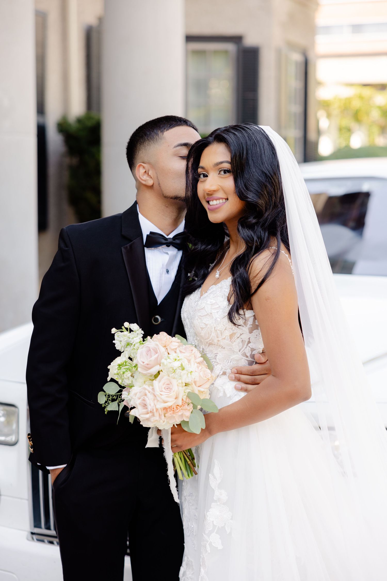 An intimate wedding portrait featuring a tender moment and beautiful bridal bouquet.