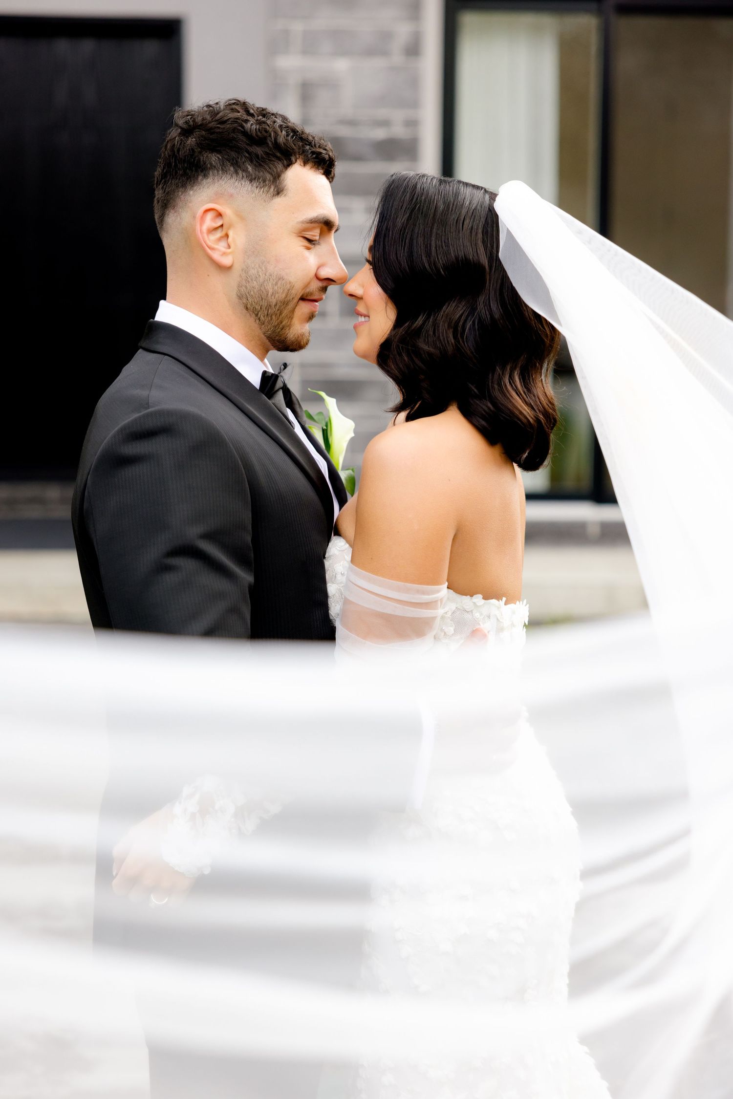 An intimate wedding portrait with the veil creating a soft, romantic frame.