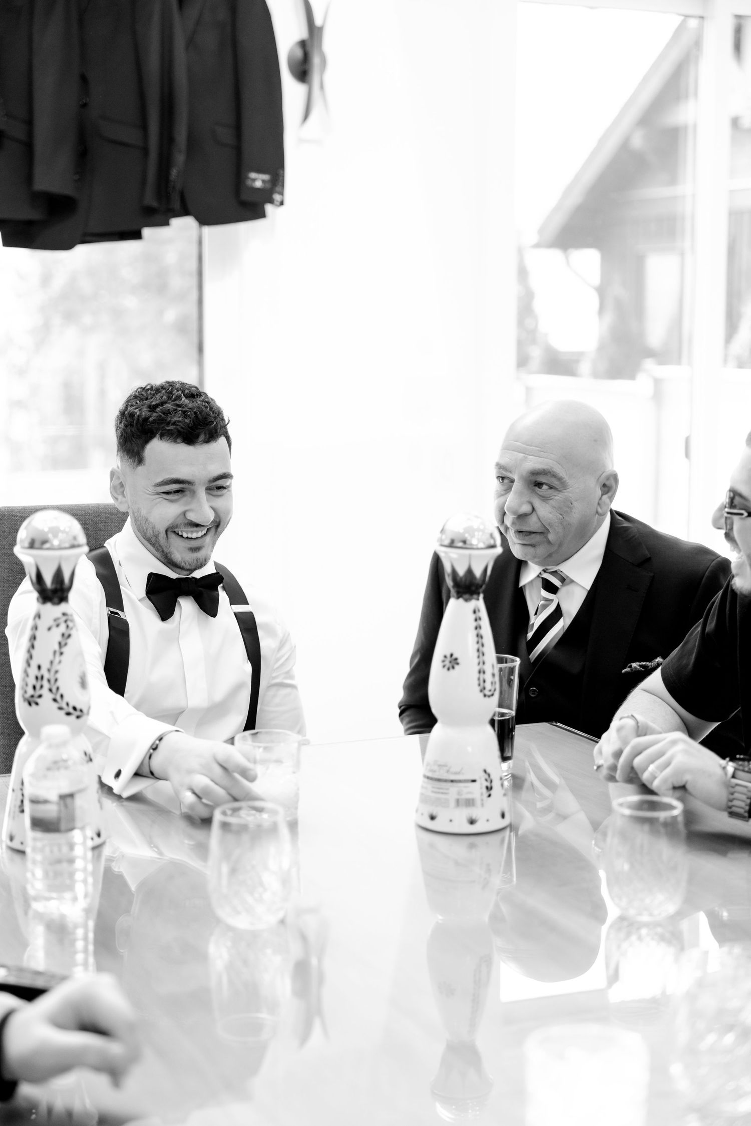 Black and white photo of people seated at table with drinks and formal attire.