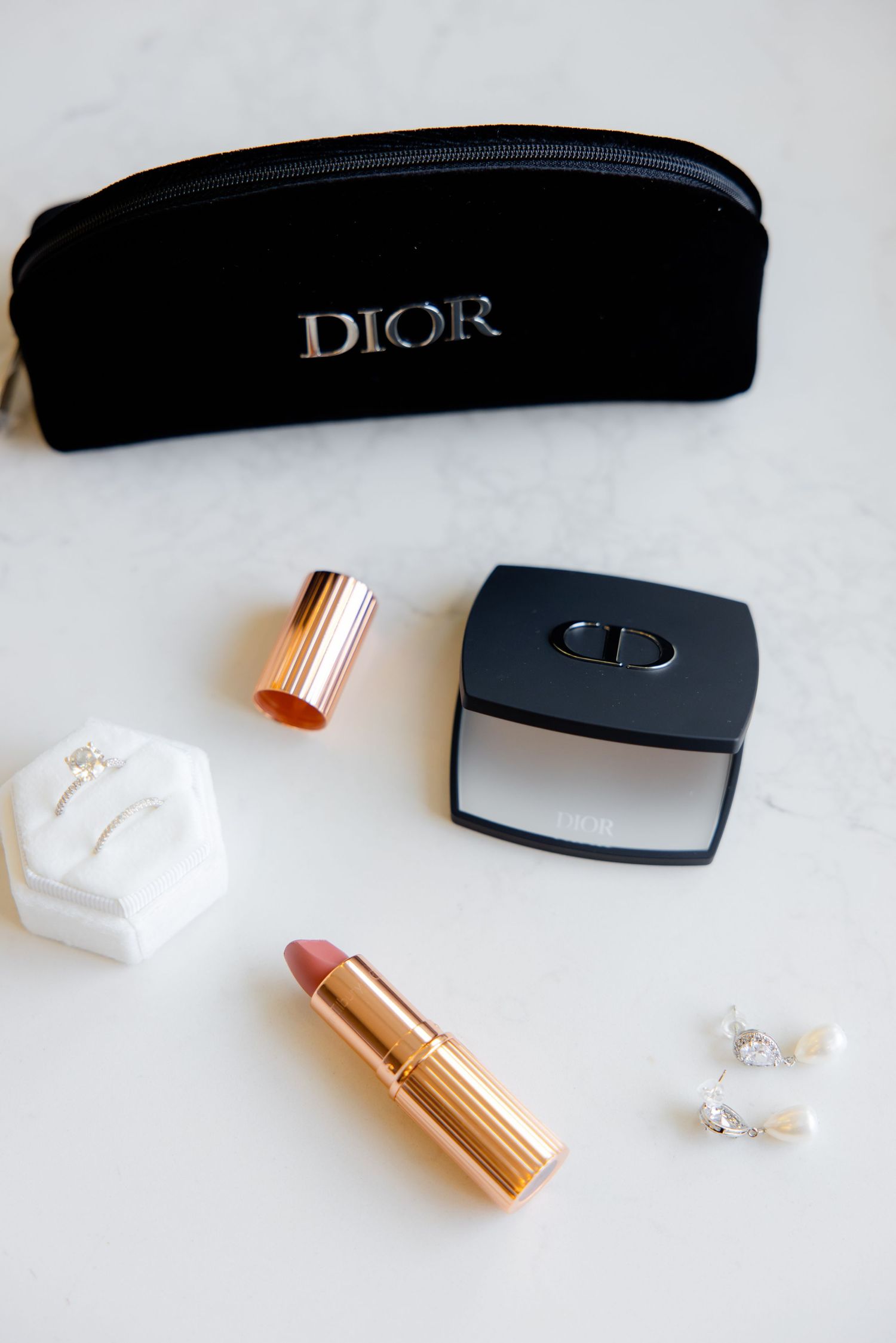 Dior beauty products including lipstick and compact displayed with black cosmetic case.