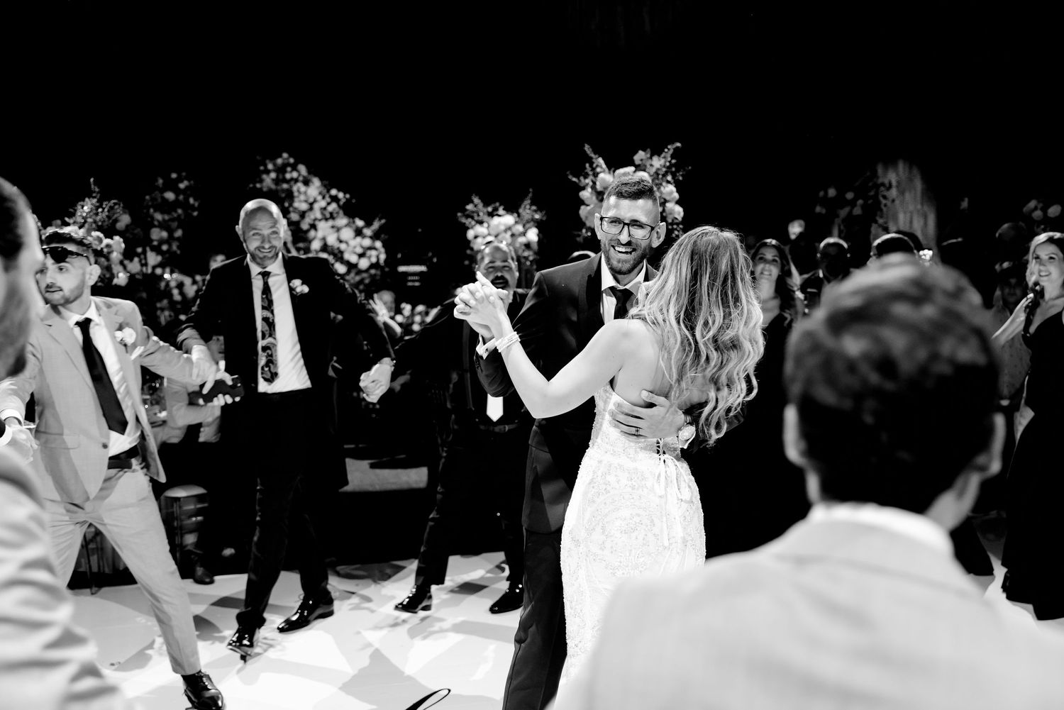 Wedding celebration dance with guests clapping and celebrating around the dance floor.