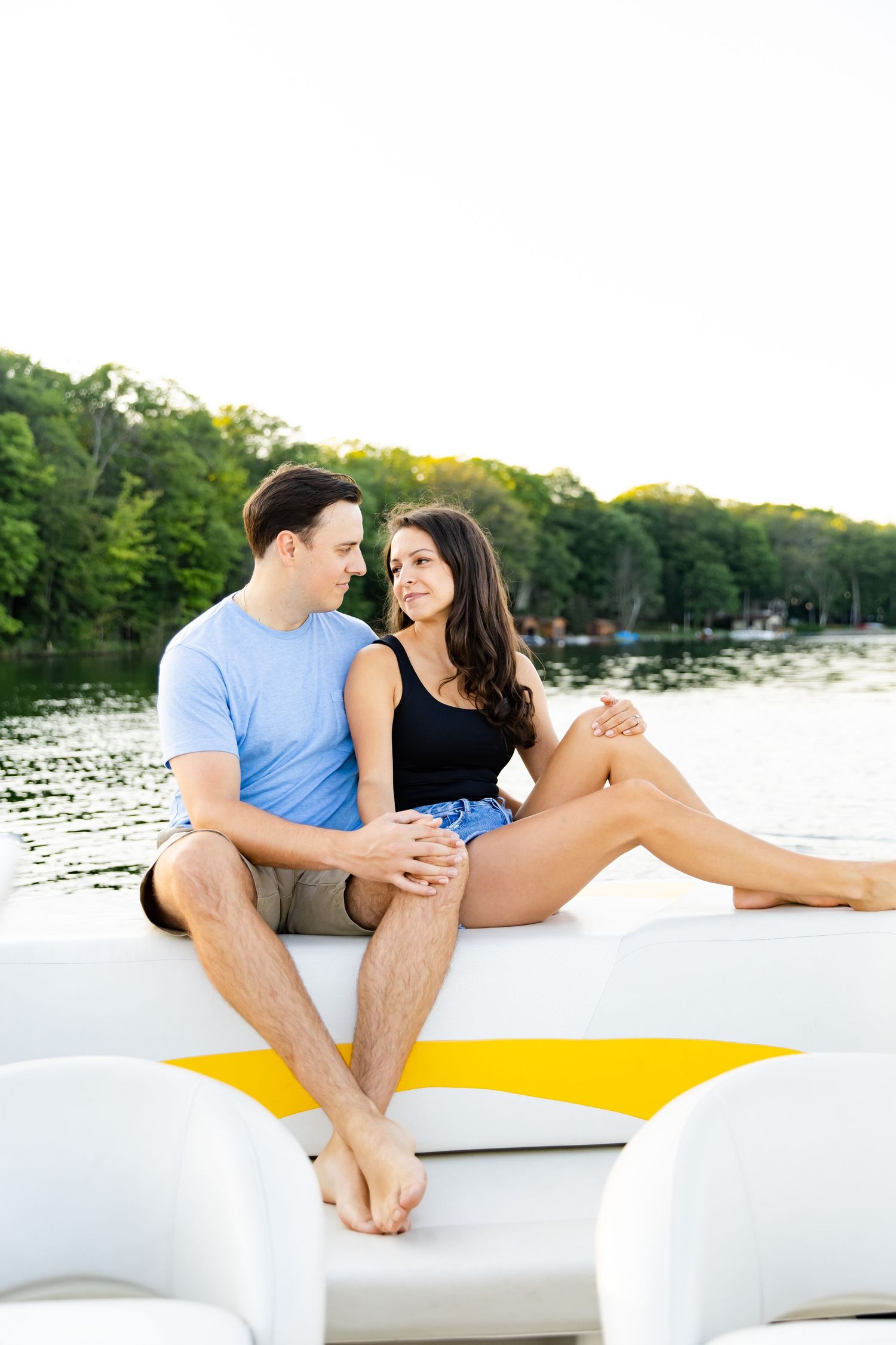 A couple sharing a tender moment while sitting on the deck of a boat on a lake.