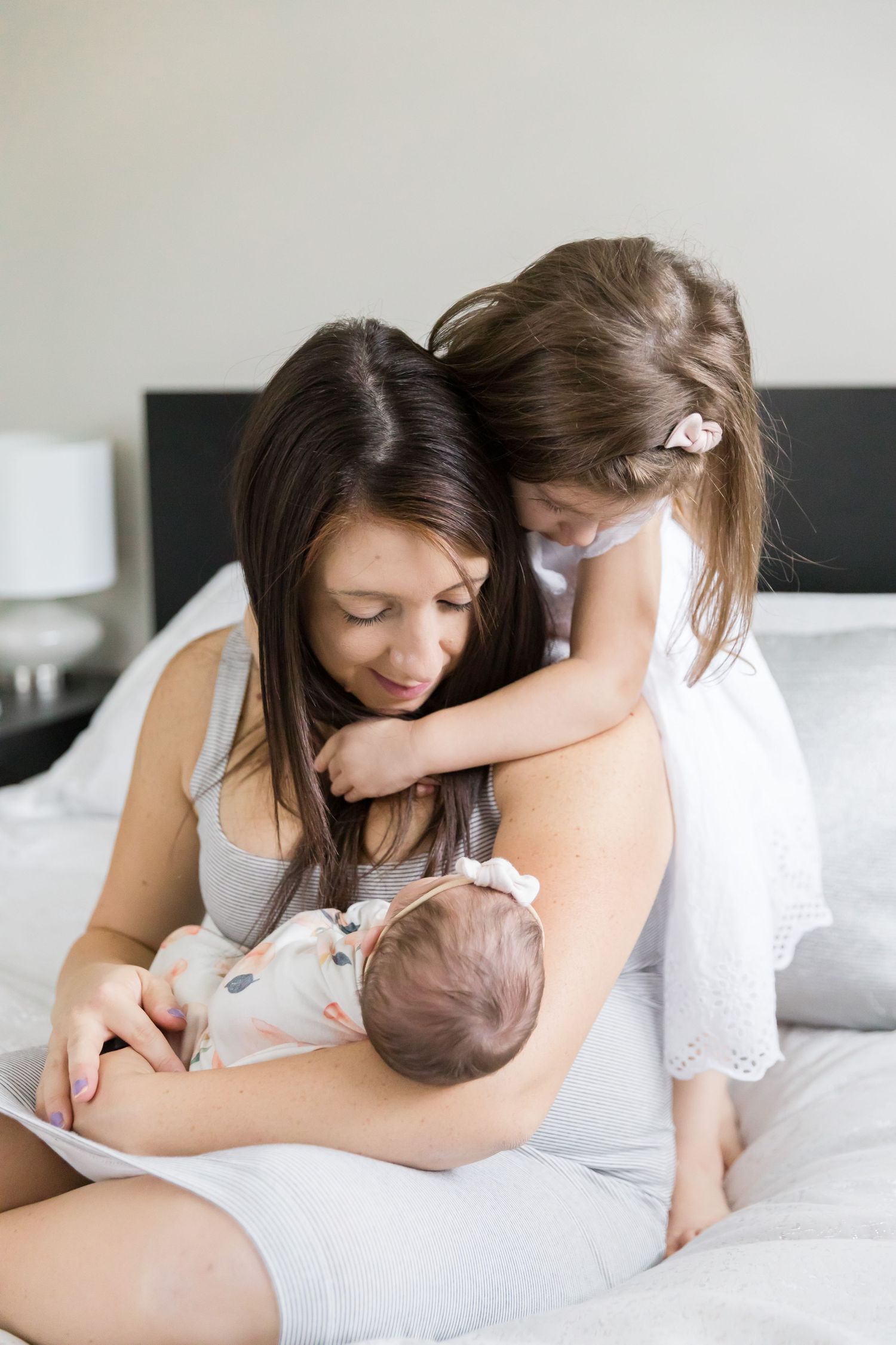 Intimate family moment with newborn baby on white bedding.