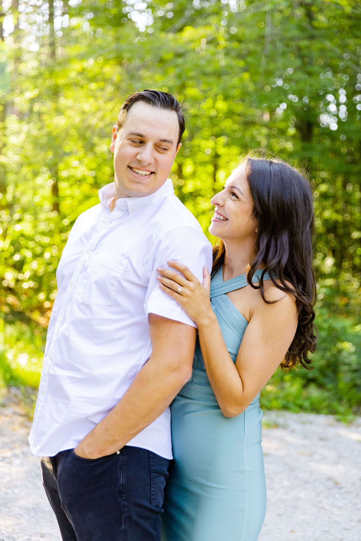 Happy couple shares a tender moment while posing together on a wooded trail.