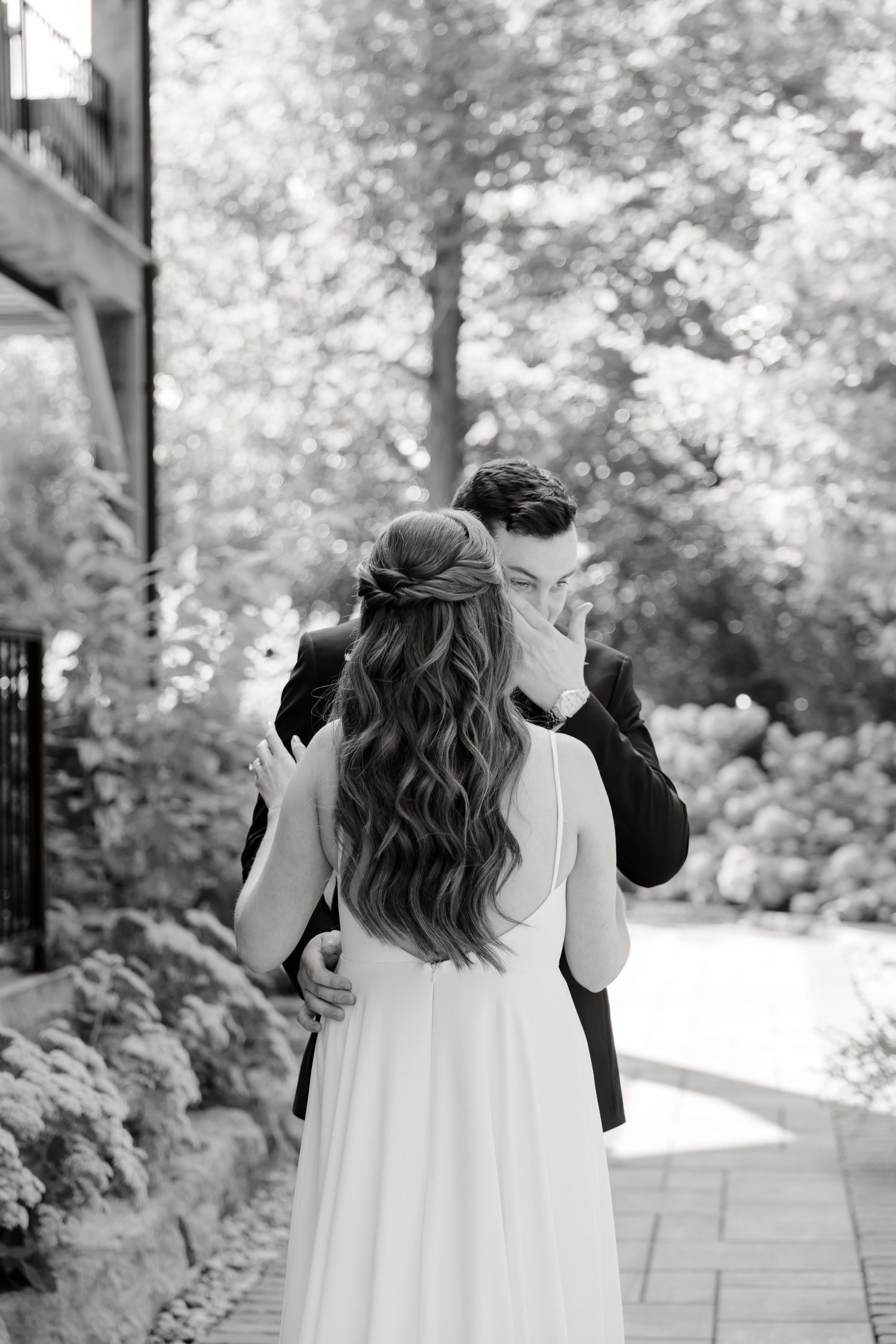 Black and white photo showing a tender wedding embrace on a winding garden path.