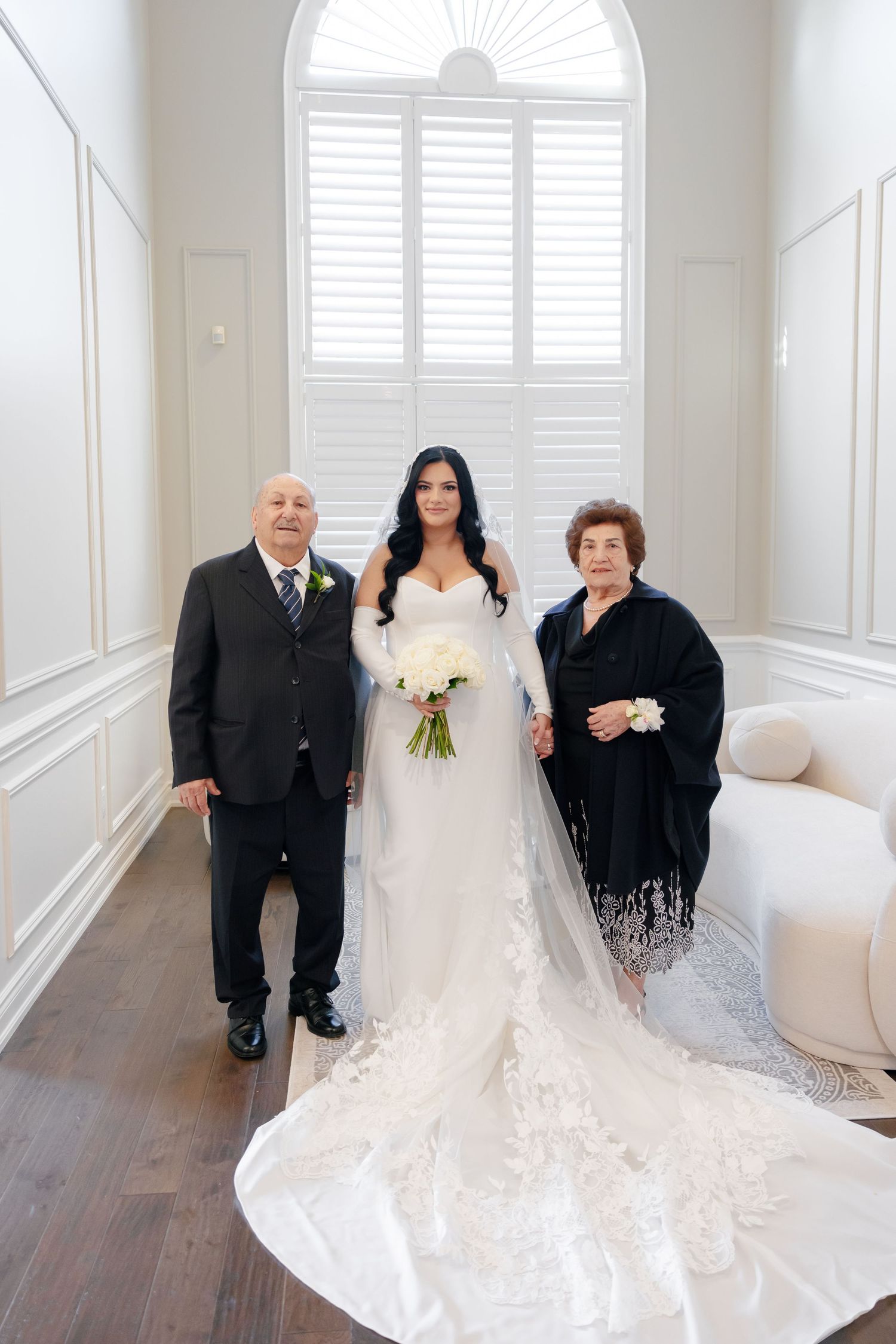 Elegant bridal portrait in bright white room with arched window and stunning lace wedding gown.