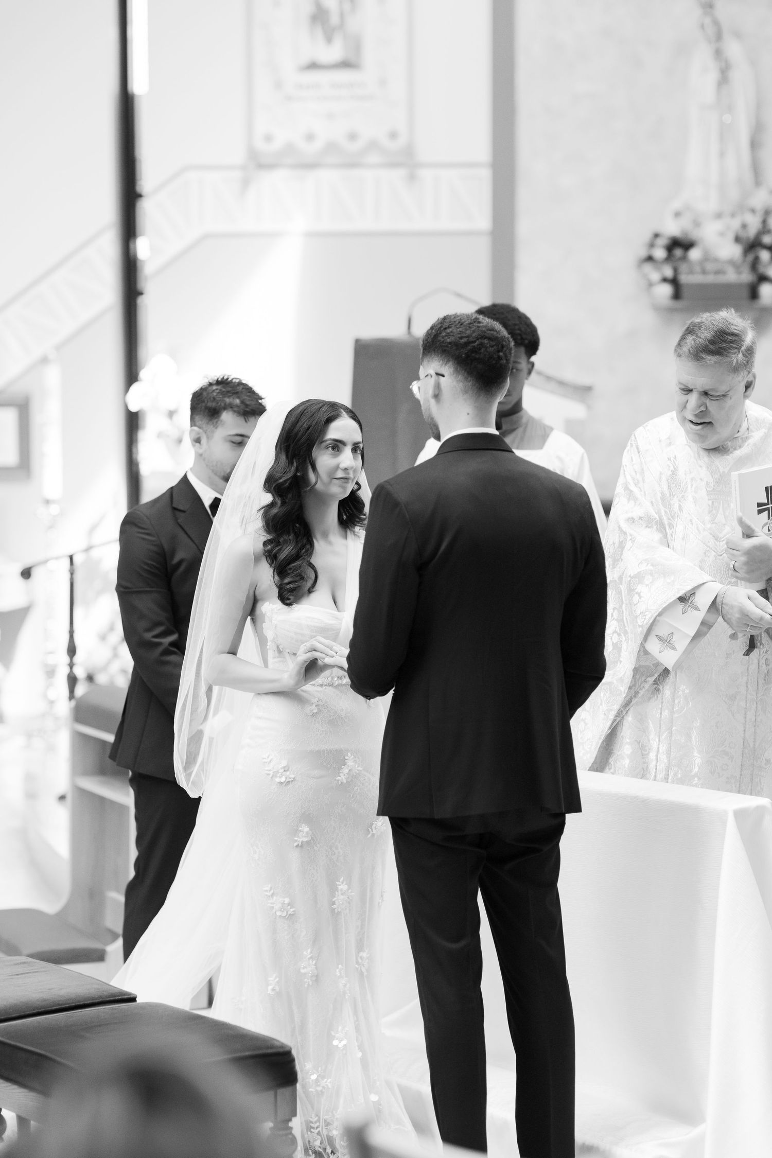 A black and white photo capturing an intimate moment during a church wedding ceremony.