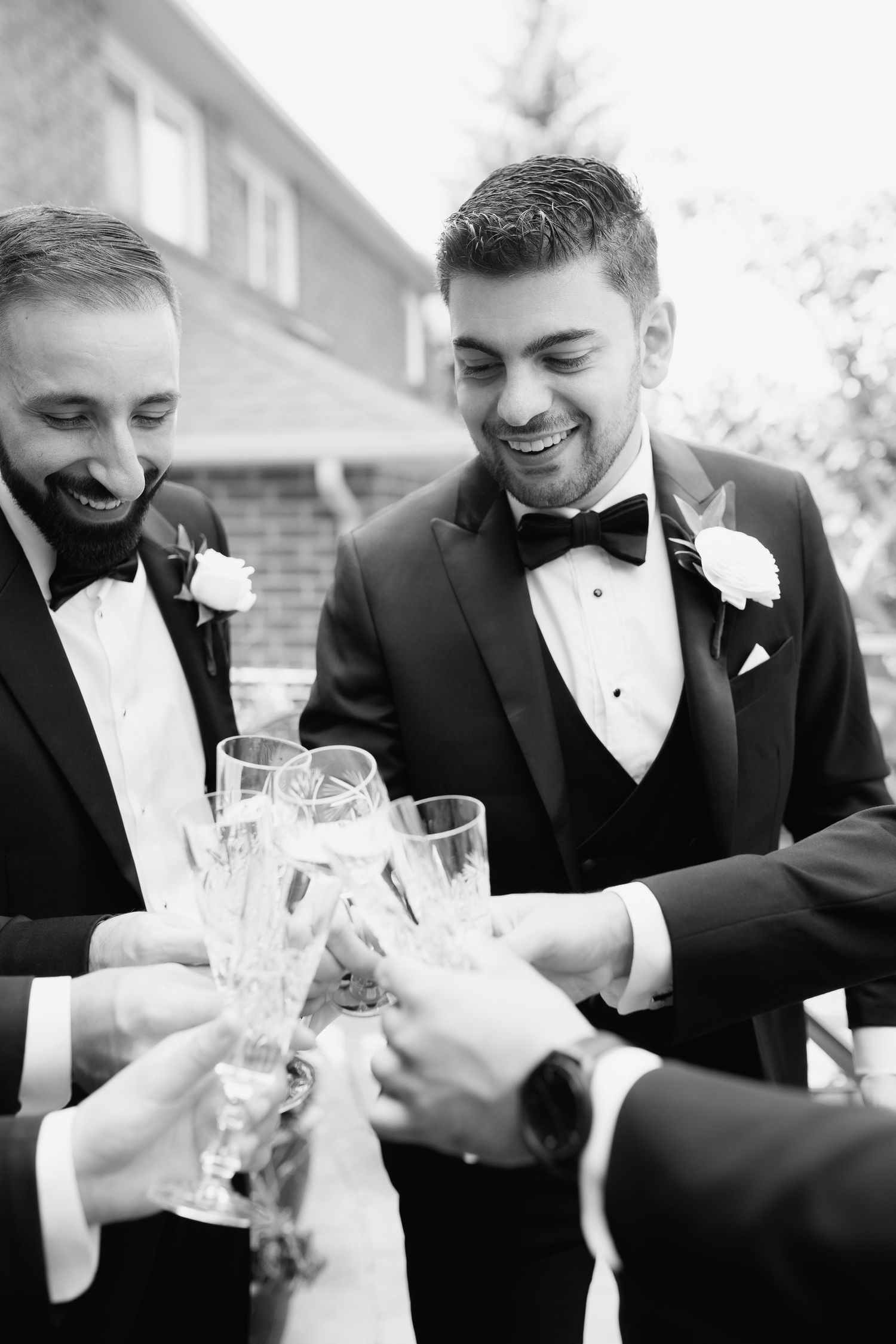 Black and white photo of tuxedo-clad guests toasting with champagne flutes.